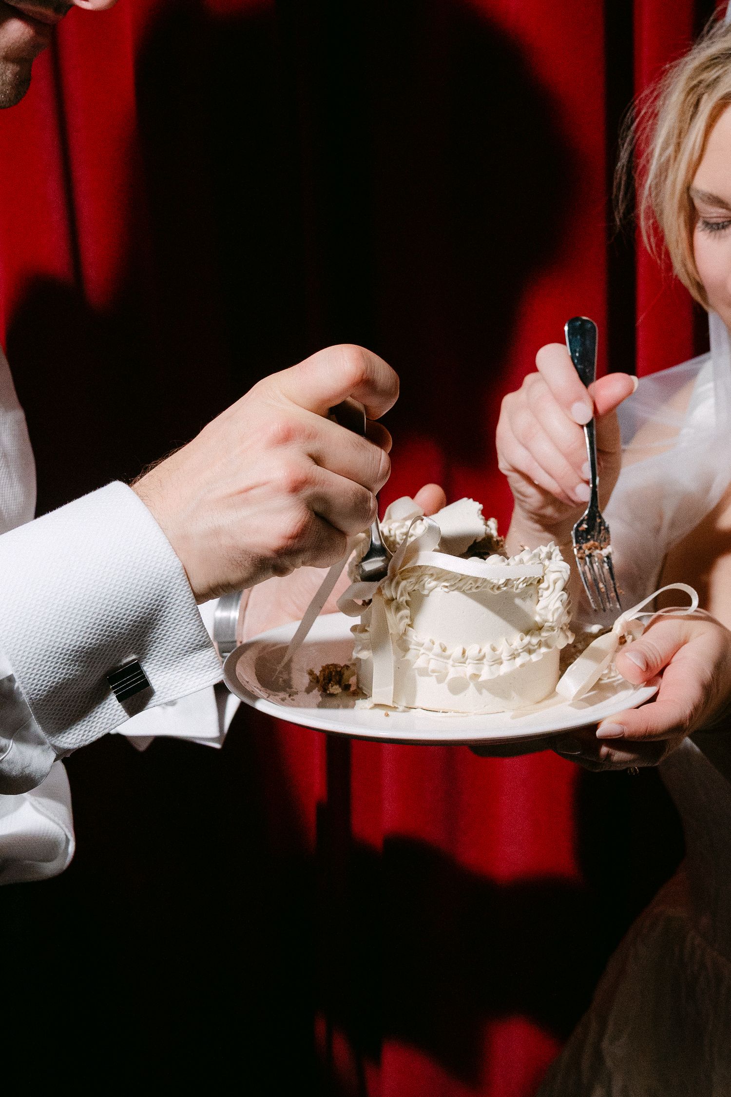Close-up view of hands holding white plates with desserts against a dramatic red background.
