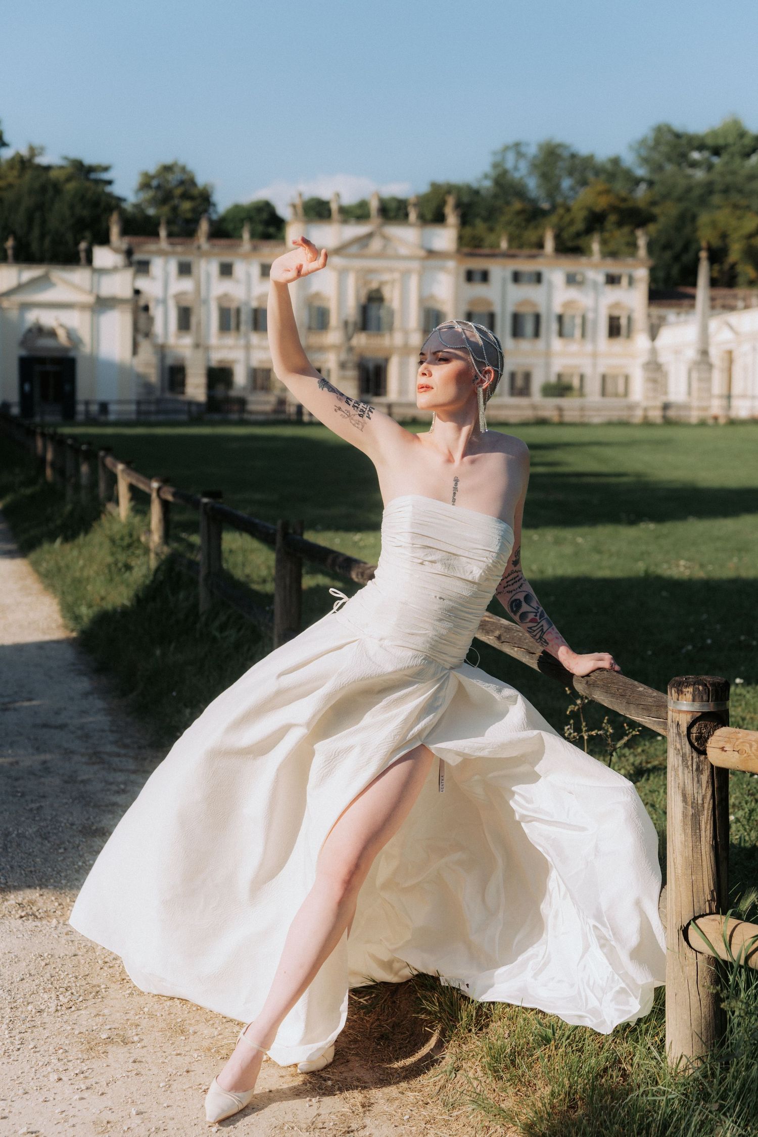 A person in a flowing white wedding dress twirls gracefully outdoors against a grand historic building backdrop.