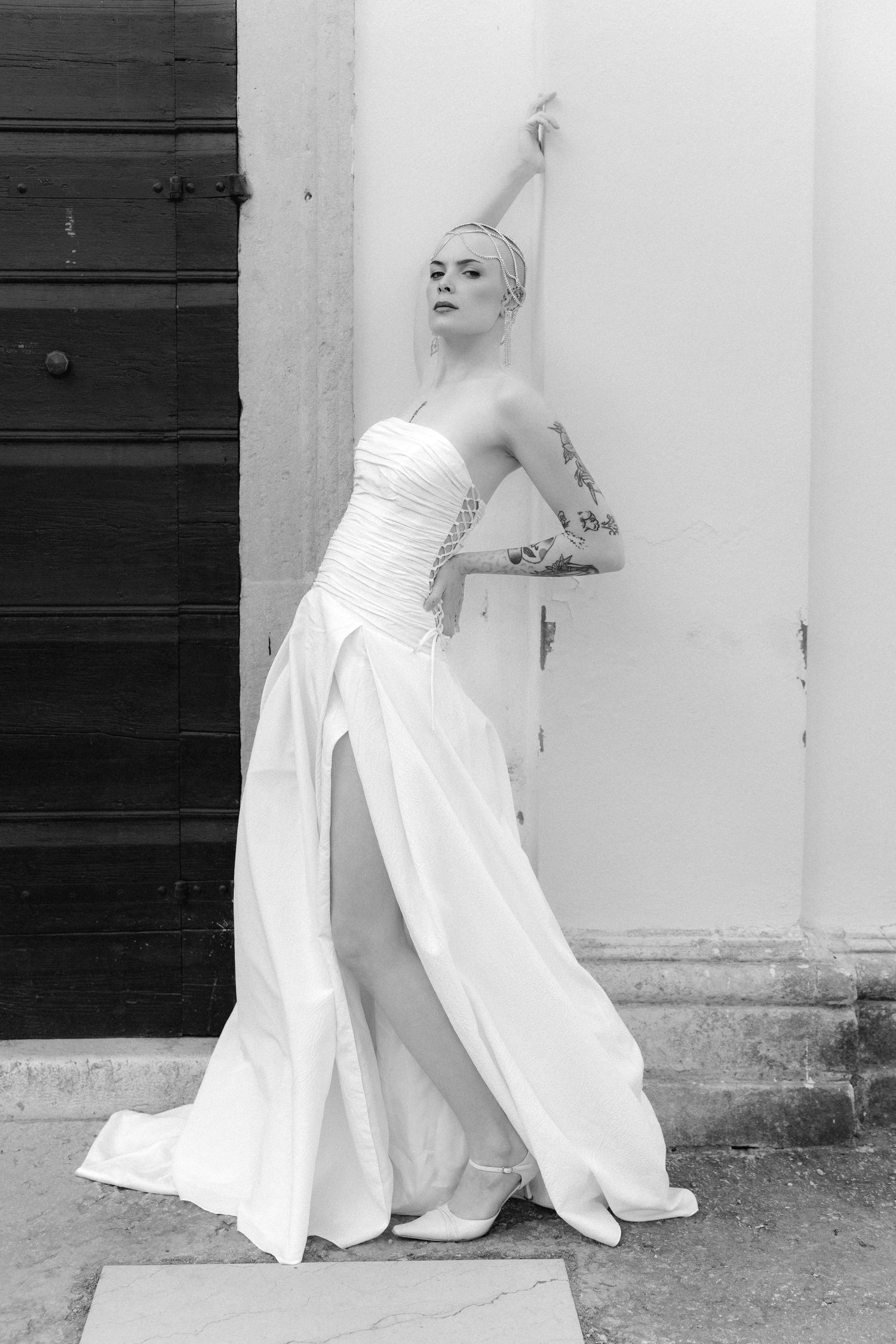A series of black and white photos showing a person in a white dress posing against a wall in different positions.