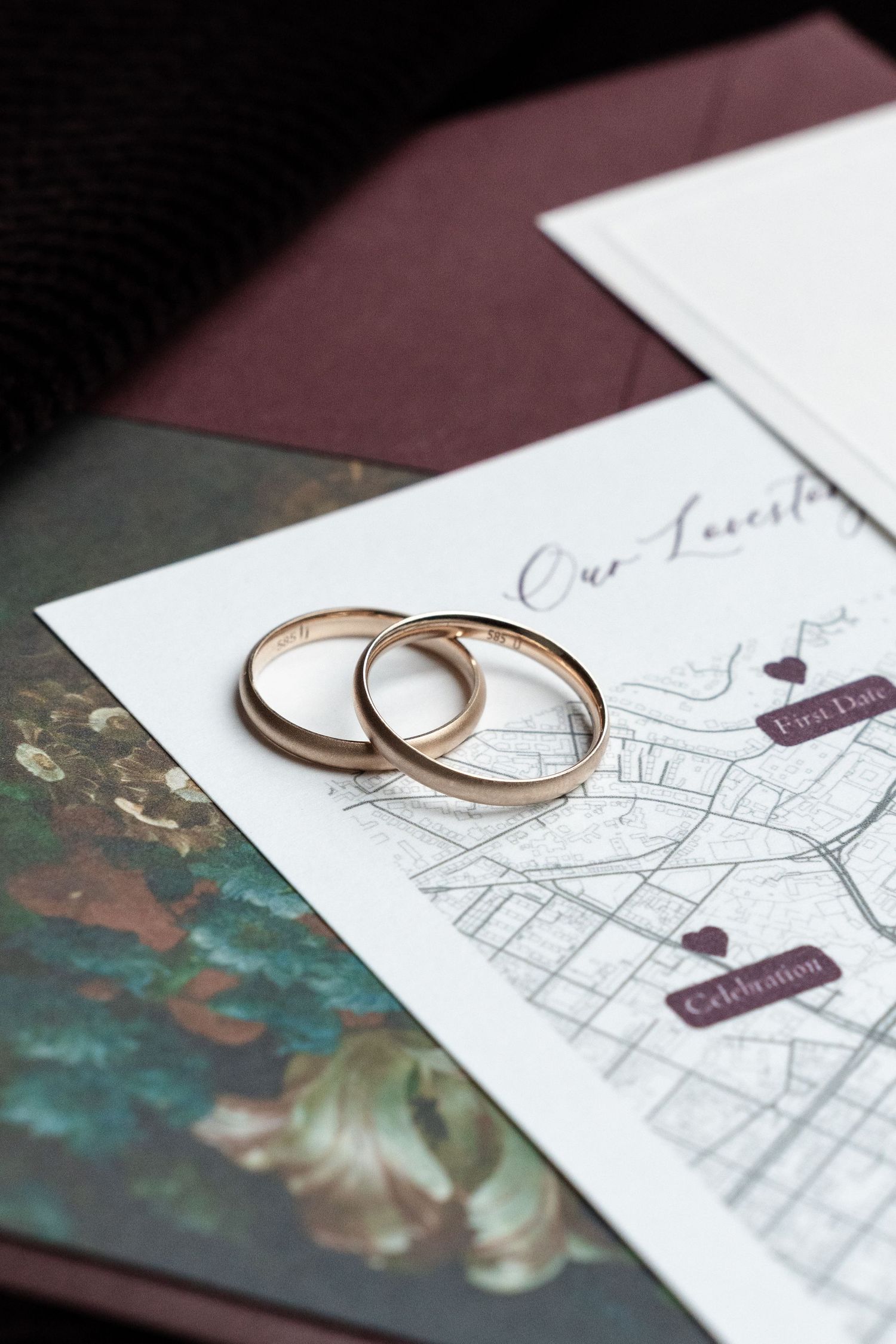 Two gold wedding rings sitting on top of a hand-drawn map with hearts and decorative details in the background.