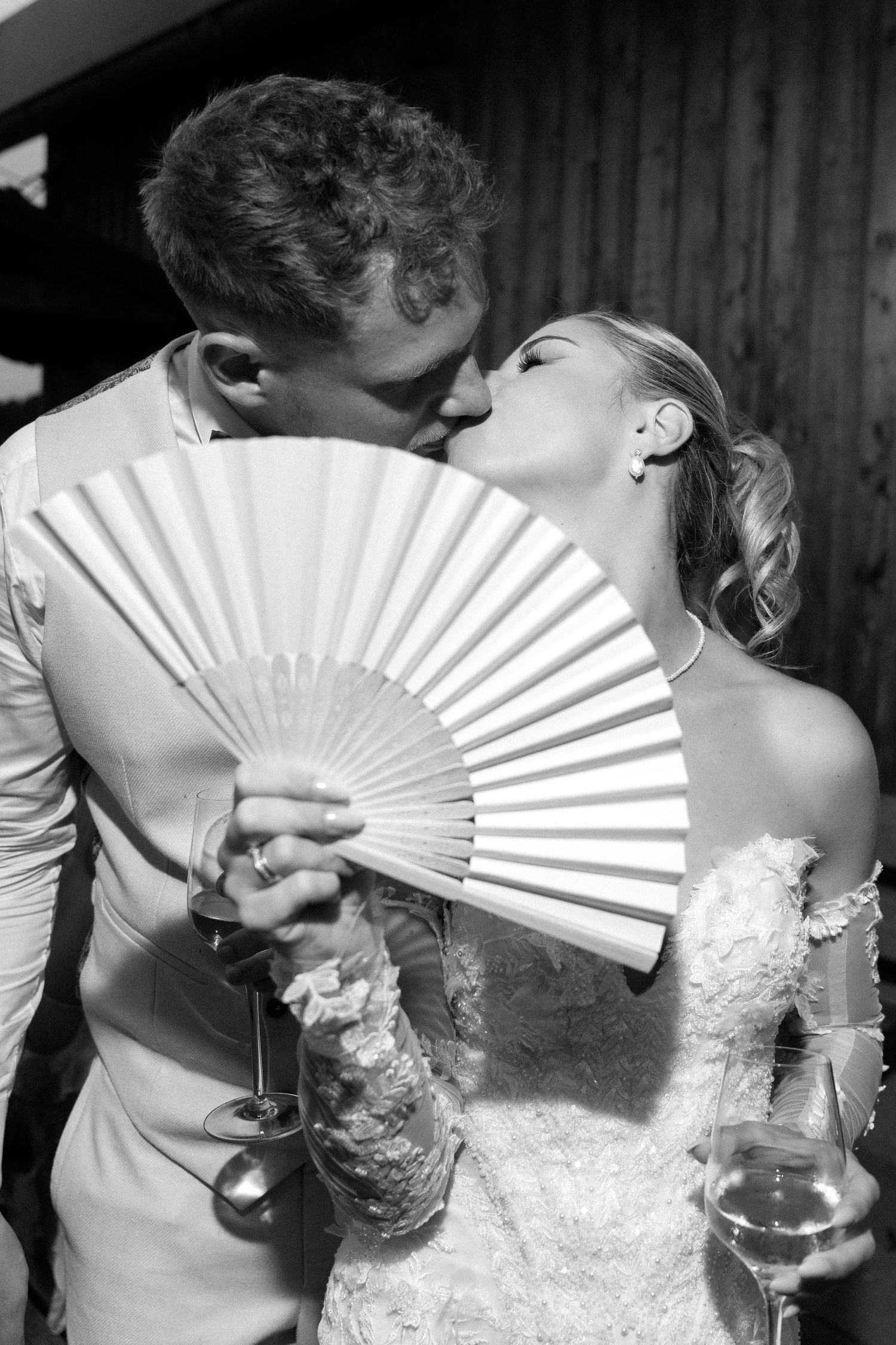A romantic black and white photo series showing a couple kissing behind a white handheld fan.