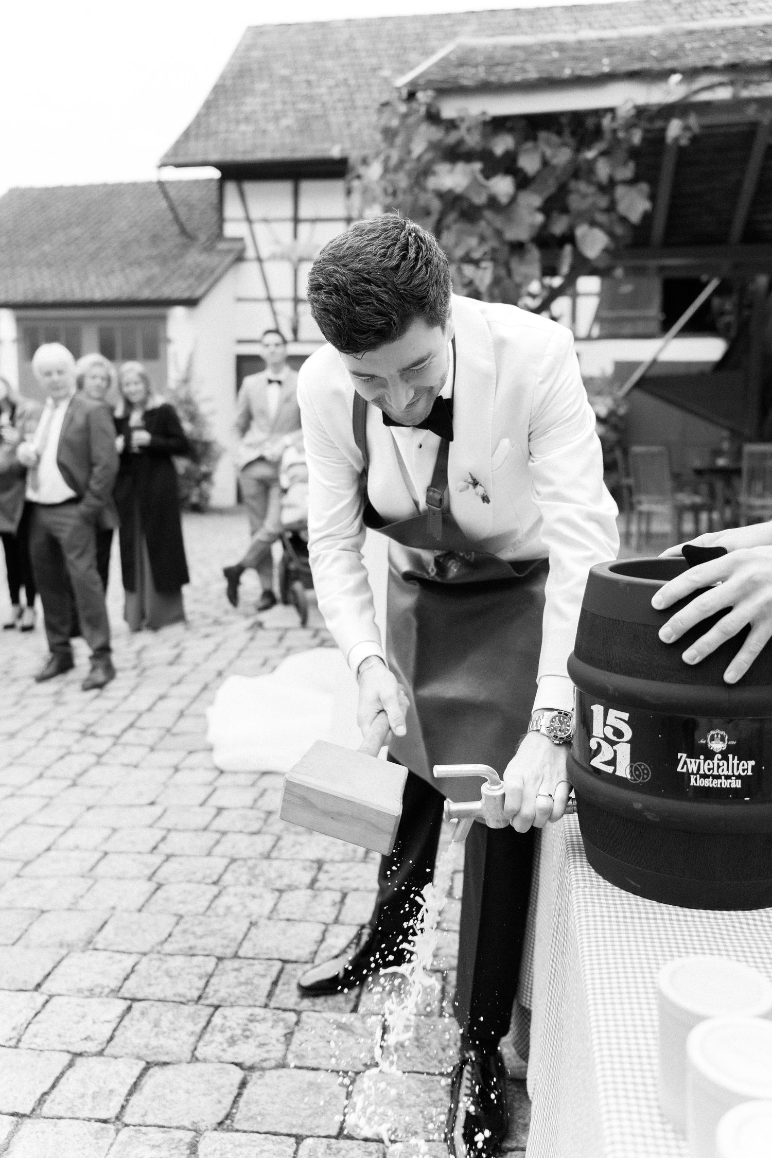 Black and white sequence shows a person in white shirt spilling coffee from a black container on stone pavement.