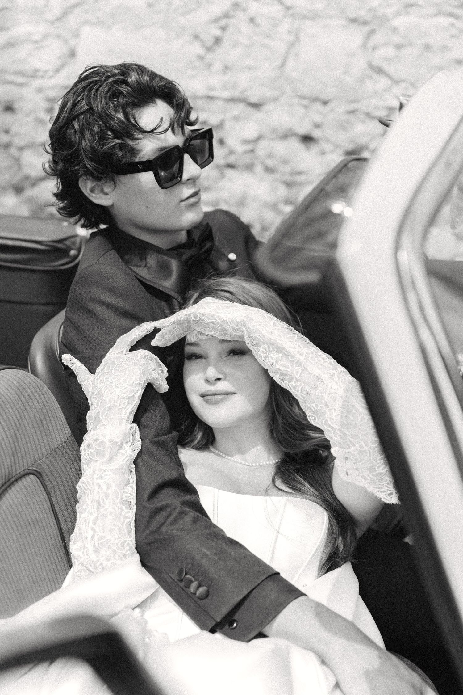 A series of black and white photos showing a couple in a car, with one person wearing sunglasses and the other in white.