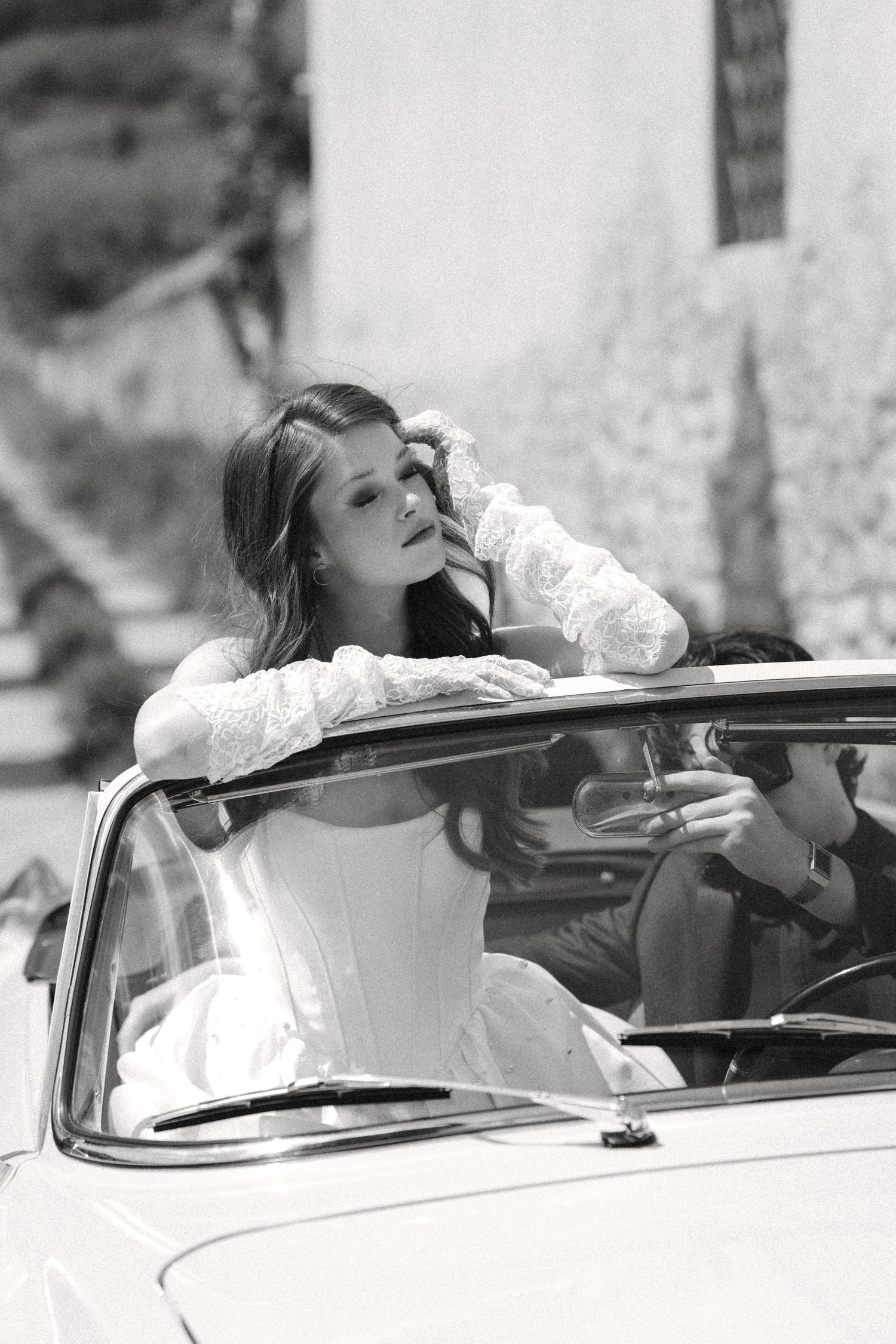 Black and white photo series showing someone reclining in a convertible car with their head tilted back.