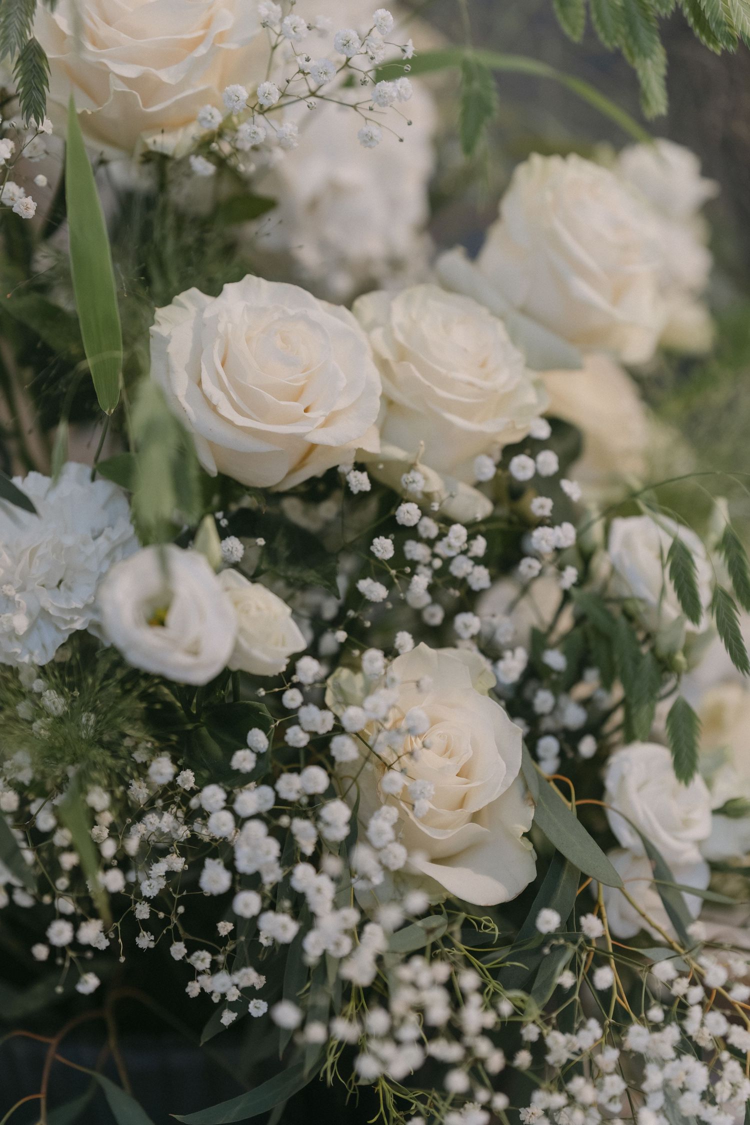 Close-up of a white rose and baby's breath wedding bouquet with ivory blooms and green foliage.