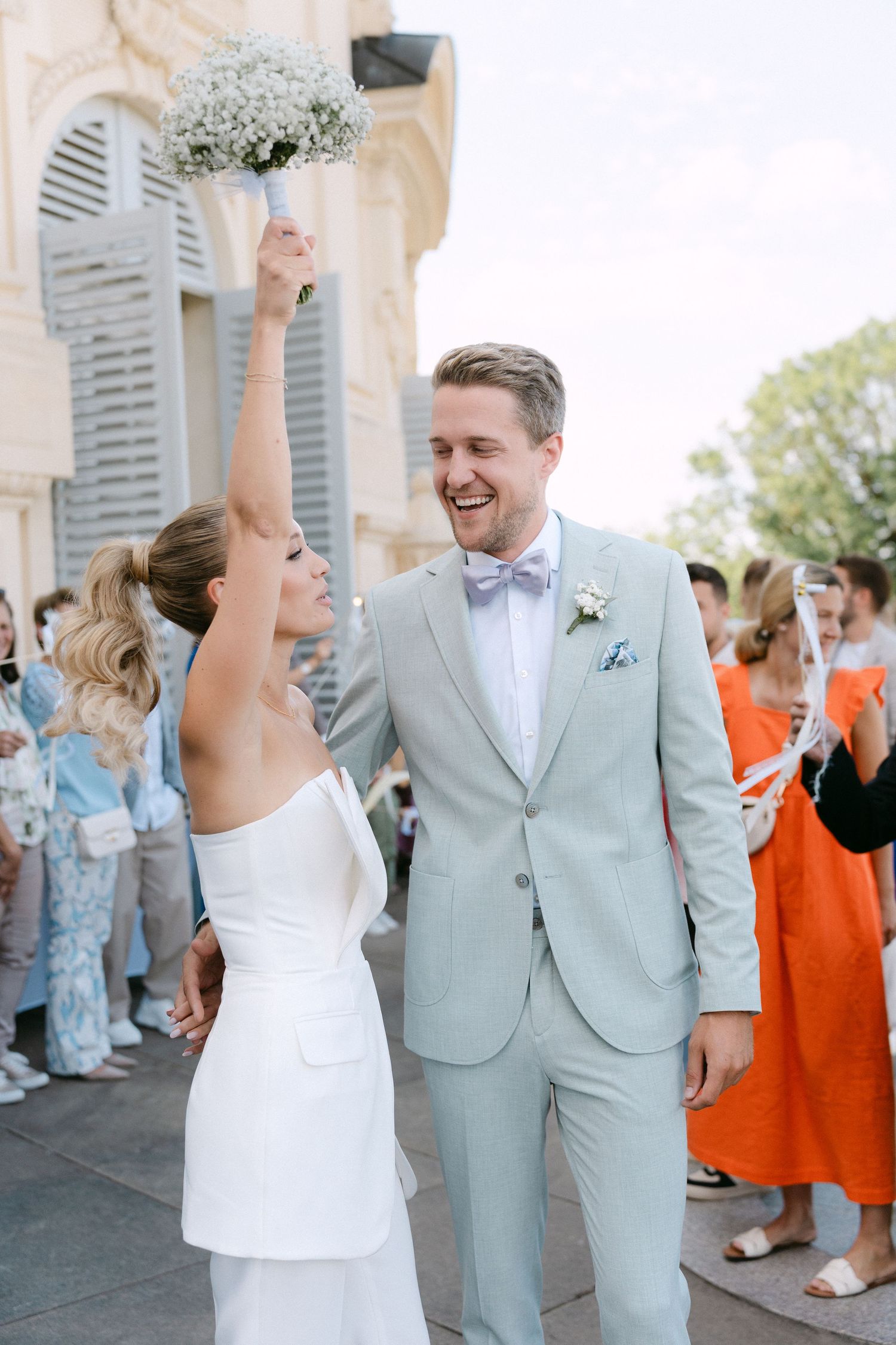 Wedding couple dancing together outdoors in mint green suit and white dress while guests watch and celebrate. Schloss Solitude