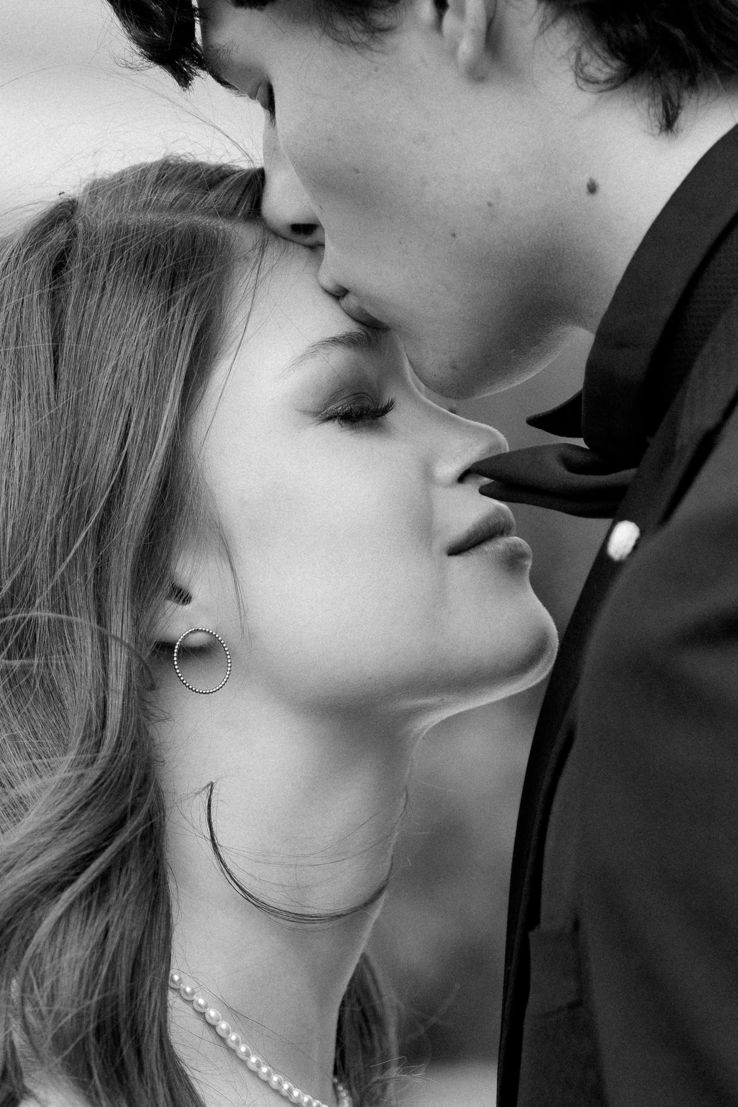 A black and white romantic close-up photo of a couple sharing an intimate kiss.