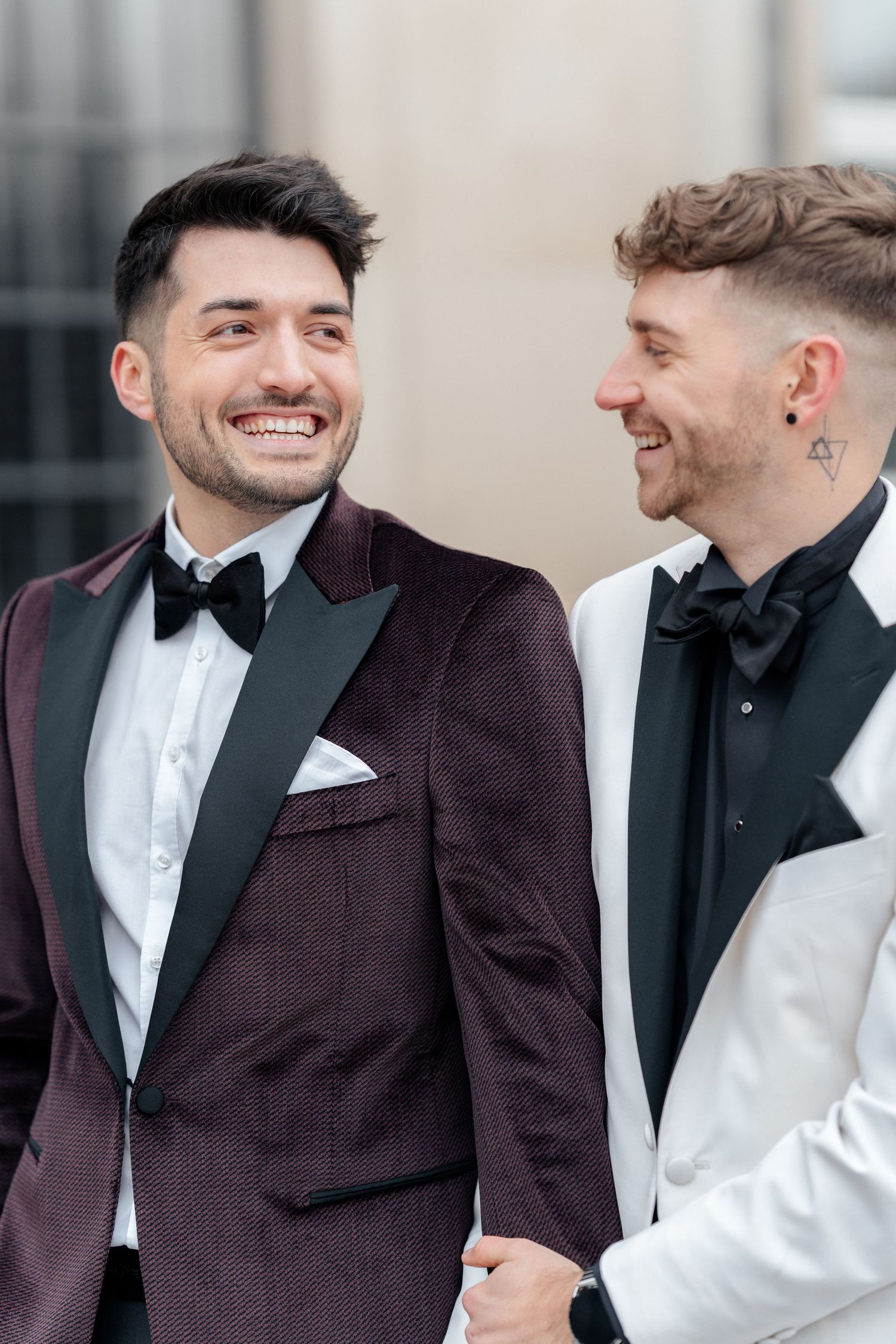 Two people share a joyful moment together while wearing formal tuxedos with bowties at a special occasion.