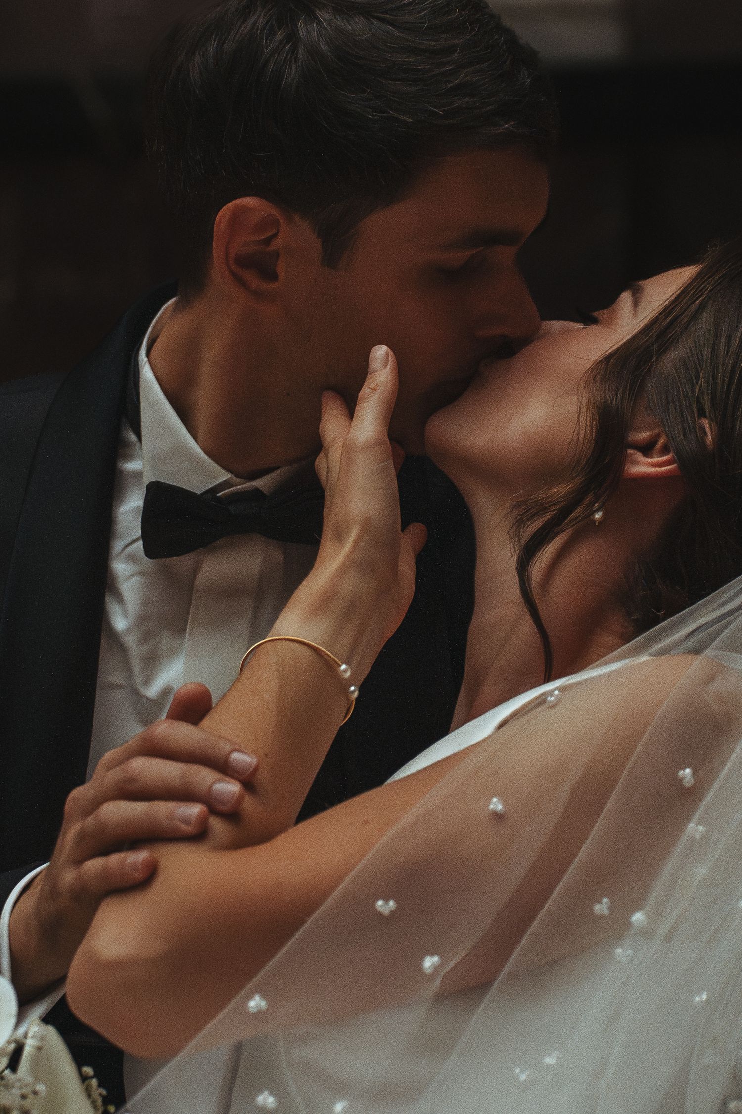 Romantic close-up of an intimate wedding moment in moody lighting.