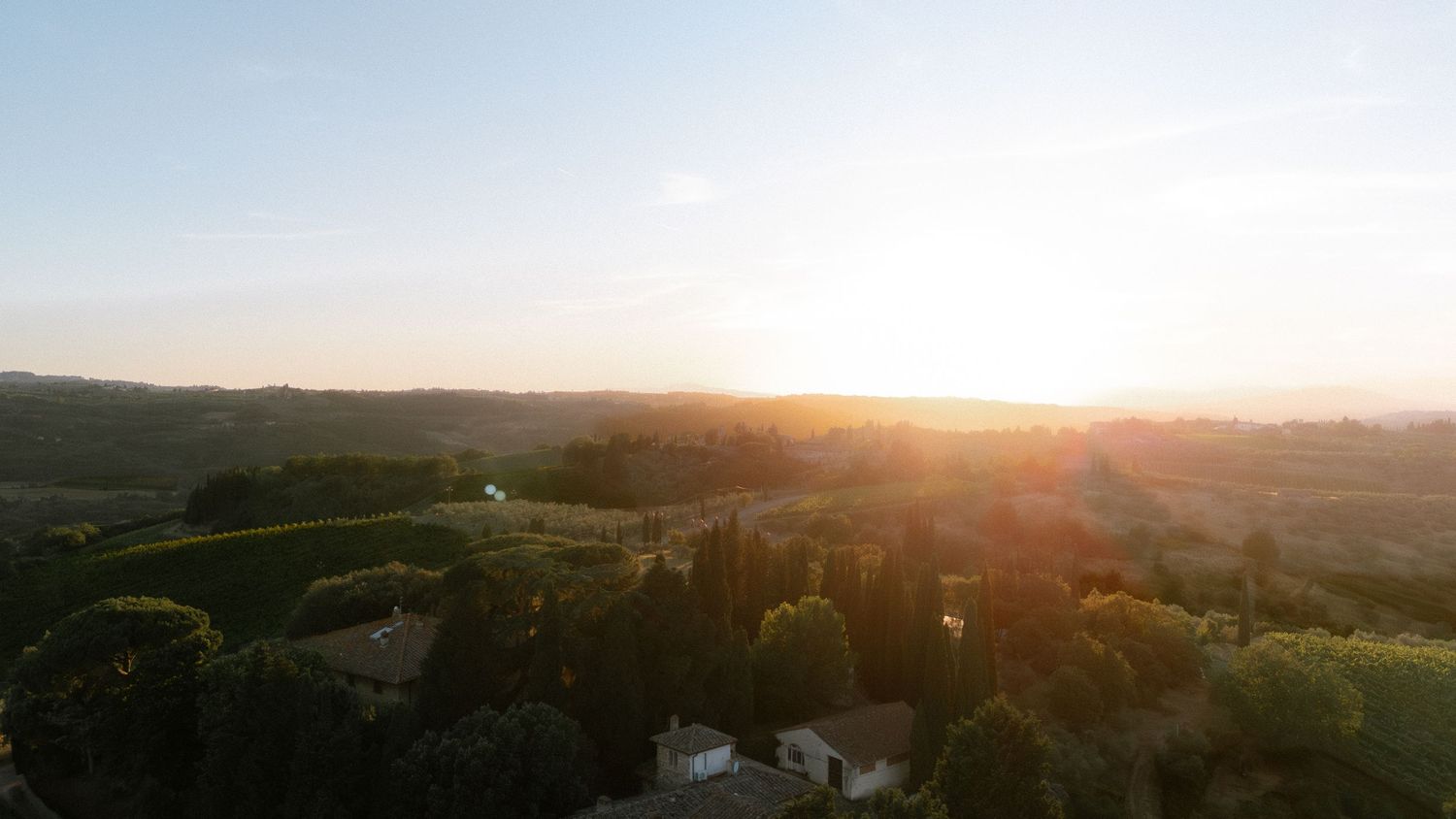 Aerial sunset view over rolling green hills and trees in a scenic countryside landscape. Tuscany.