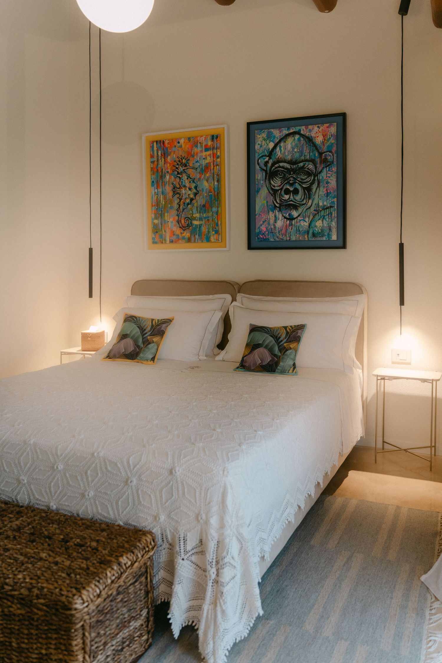 Cozy bedroom with white bedding, wooden beams, and colorful artwork on walls.