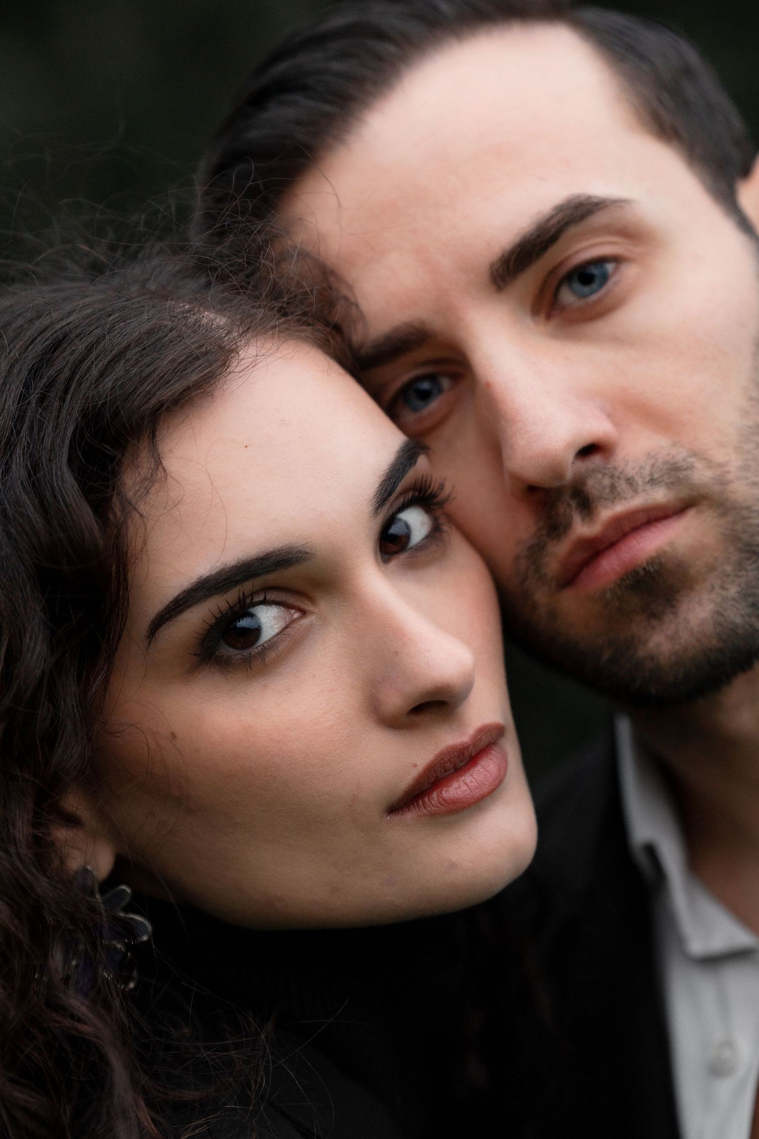 Close-up romantic portrait of a couple with intense gazes against dark background.