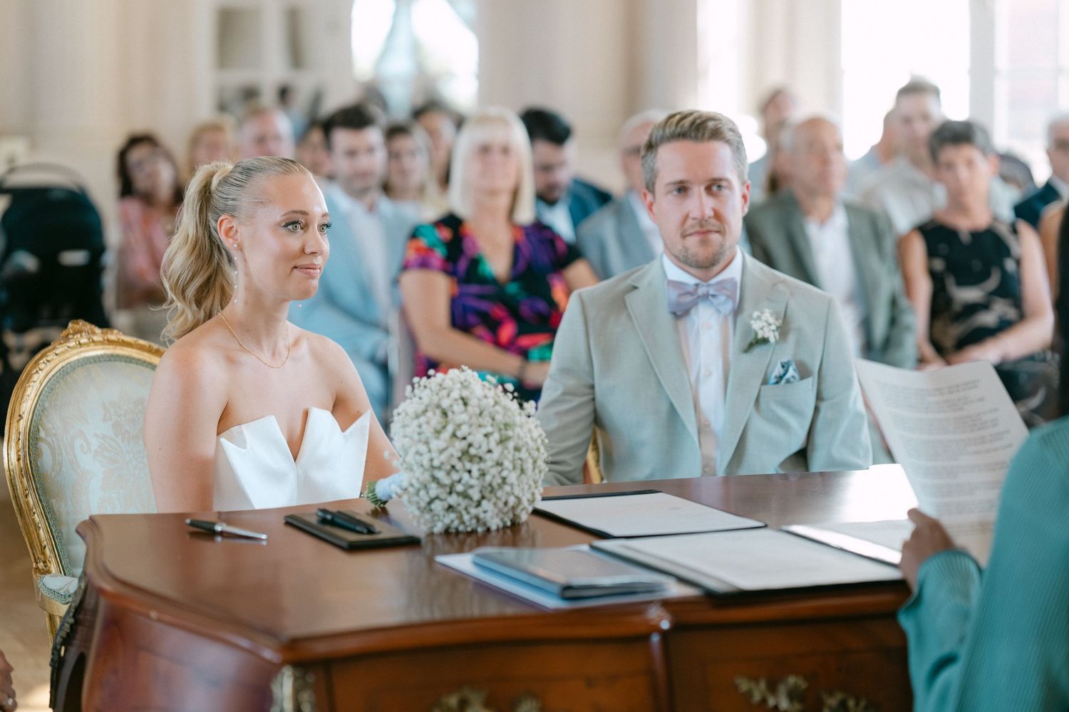 Guests sit at tables during a wedding reception in an elegant venue with soft lighting and decorative details. Schloss Solitude