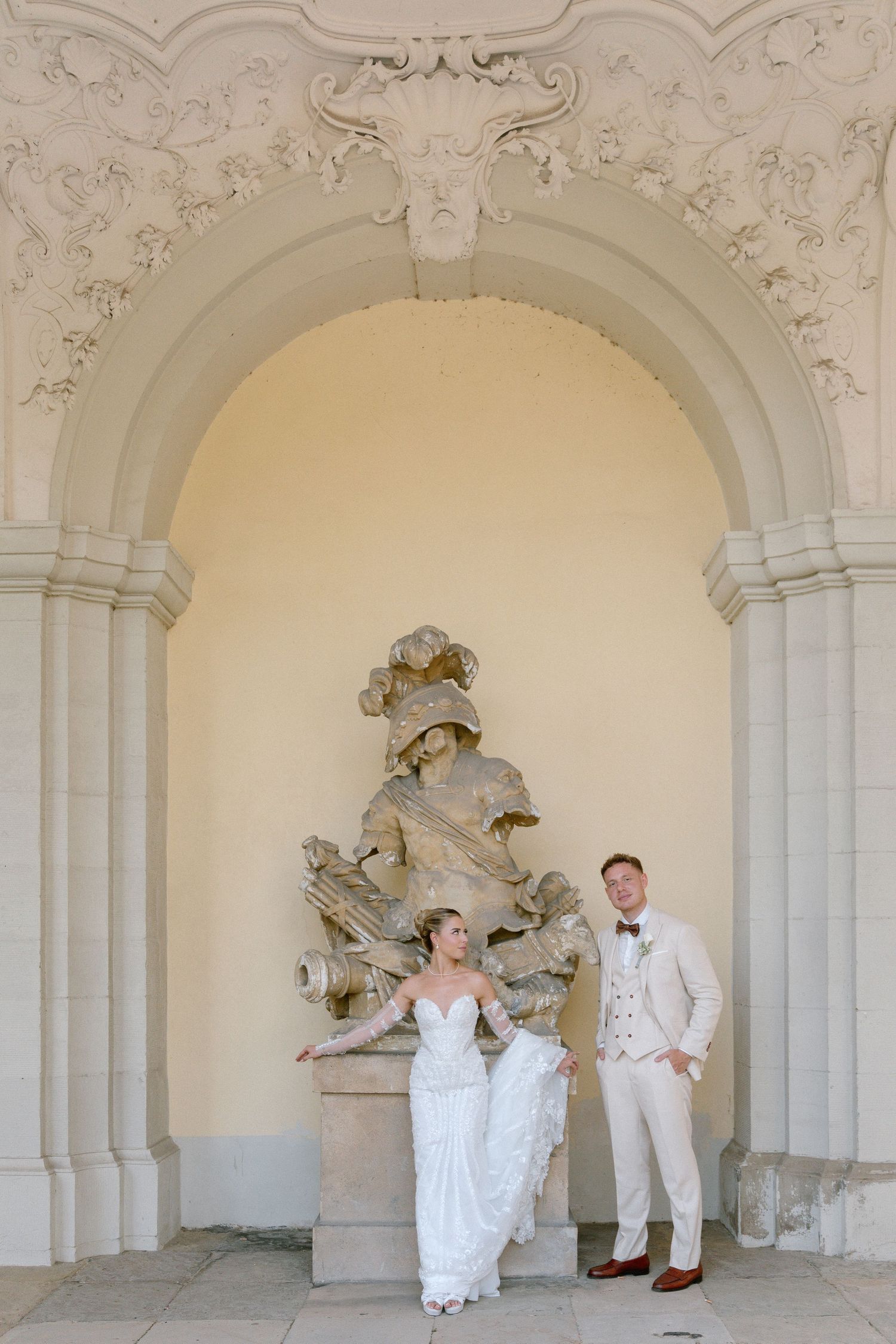 A sequence of wedding photos showing a couple posing playfully in white attire under ornate stone archways. Schloss Ludwigsburg