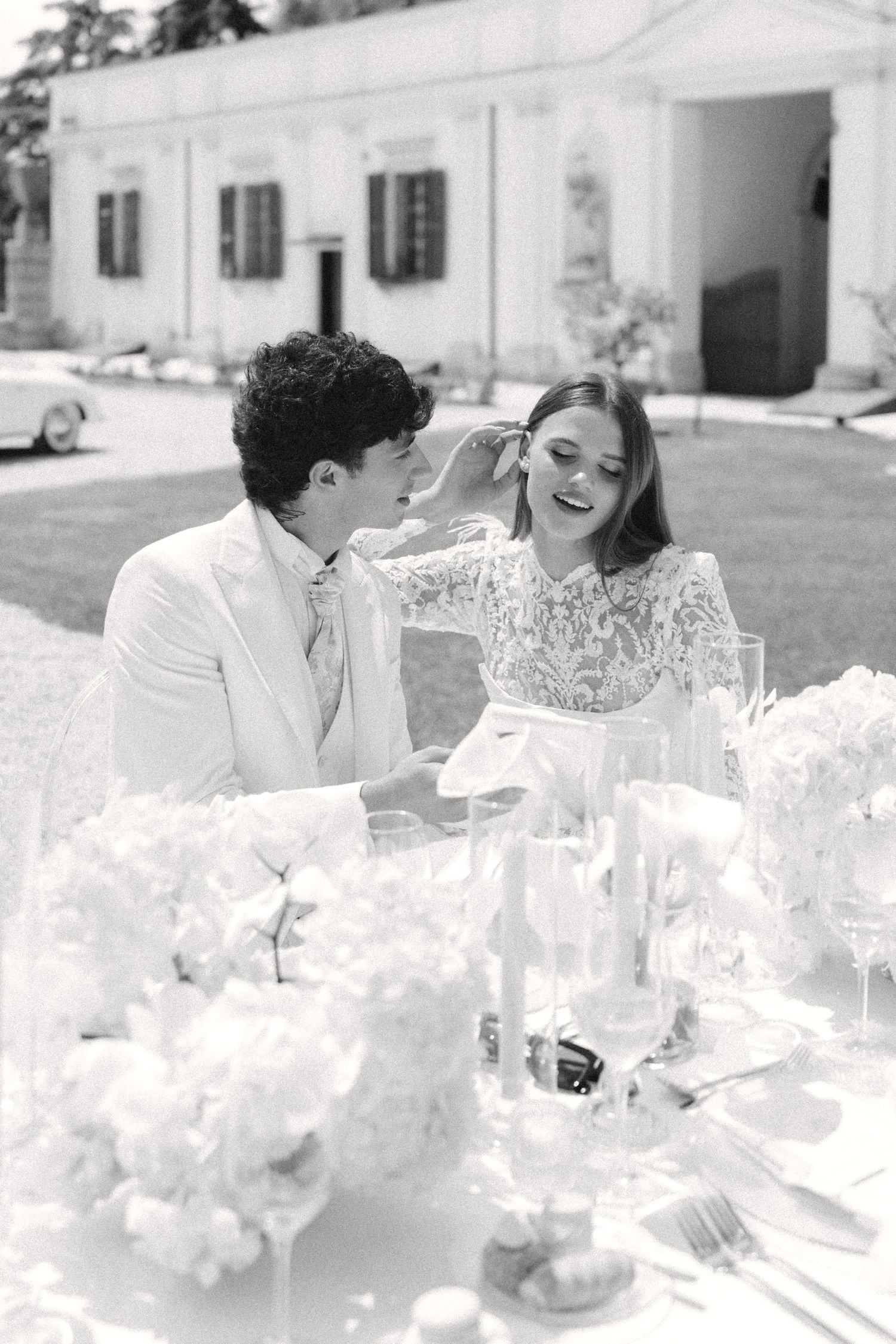 Black and white wedding reception scene with elegant table settings and floral arrangements.