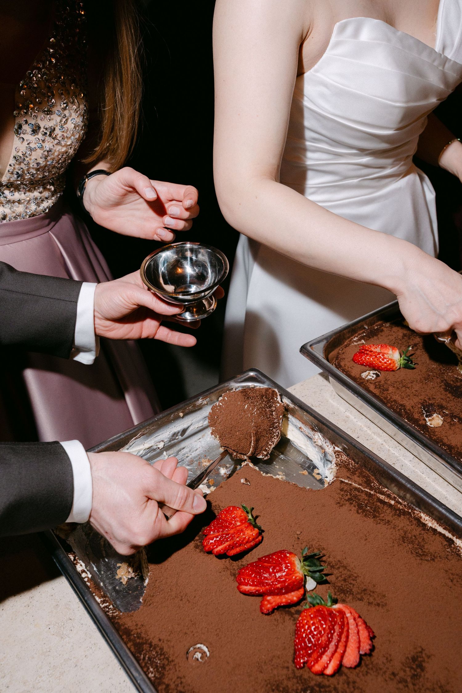 Bride and guests serving tiramisu dessert with fresh strawberries at an elegant wedding reception.