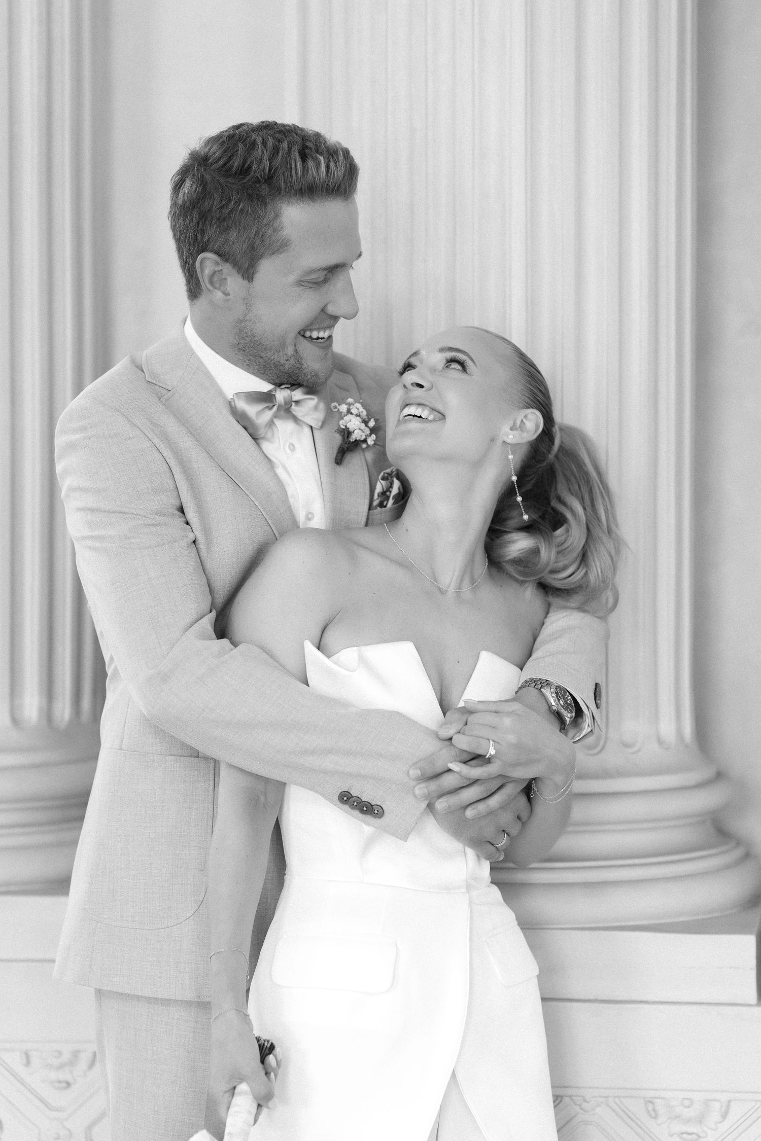 A romantic black and white photo series of a couple in white formal attire dancing and embracing near elegant columns. Schloss Solitude