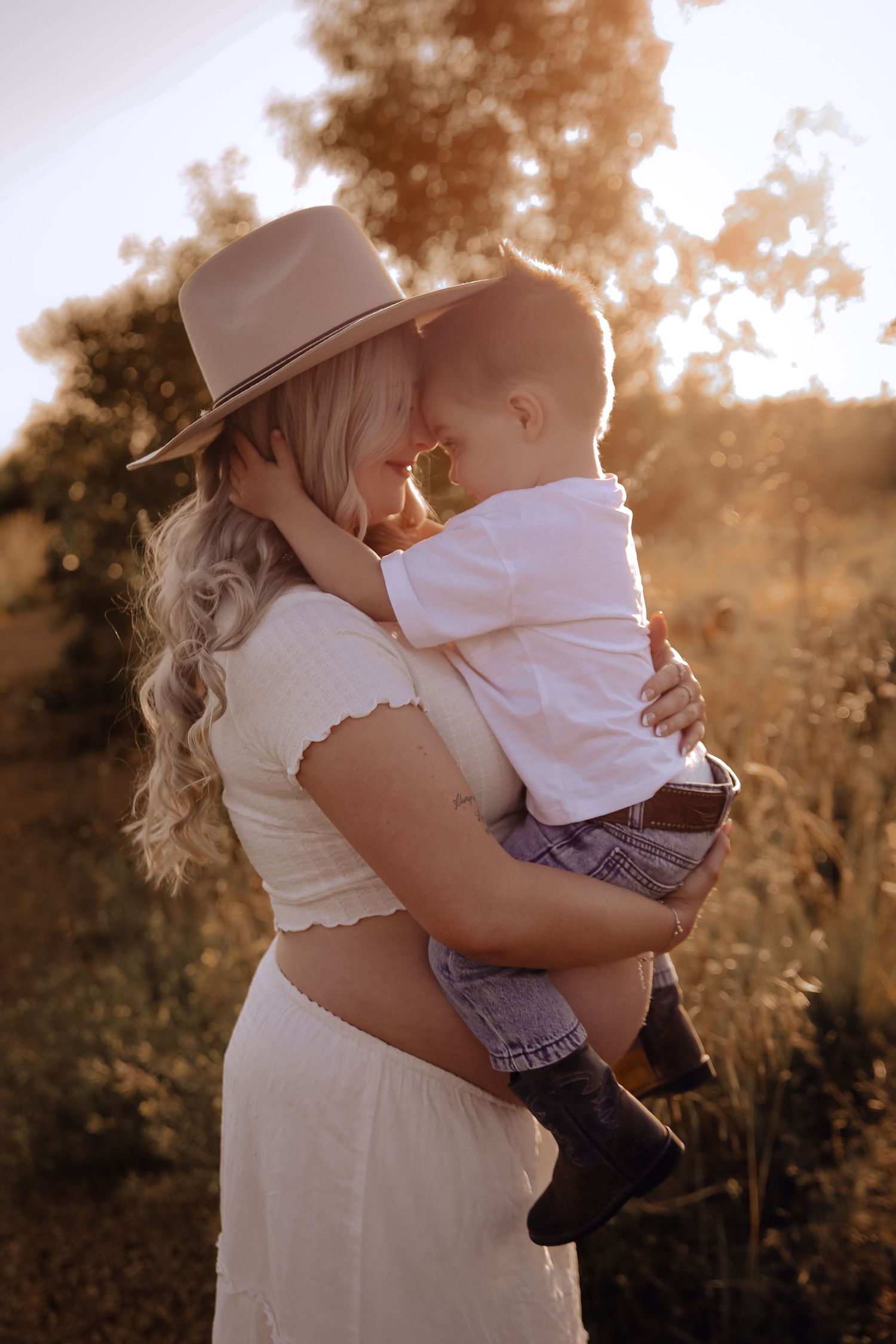 A tender moment between parent and child in a sunlit field. Mumma and Me sessions