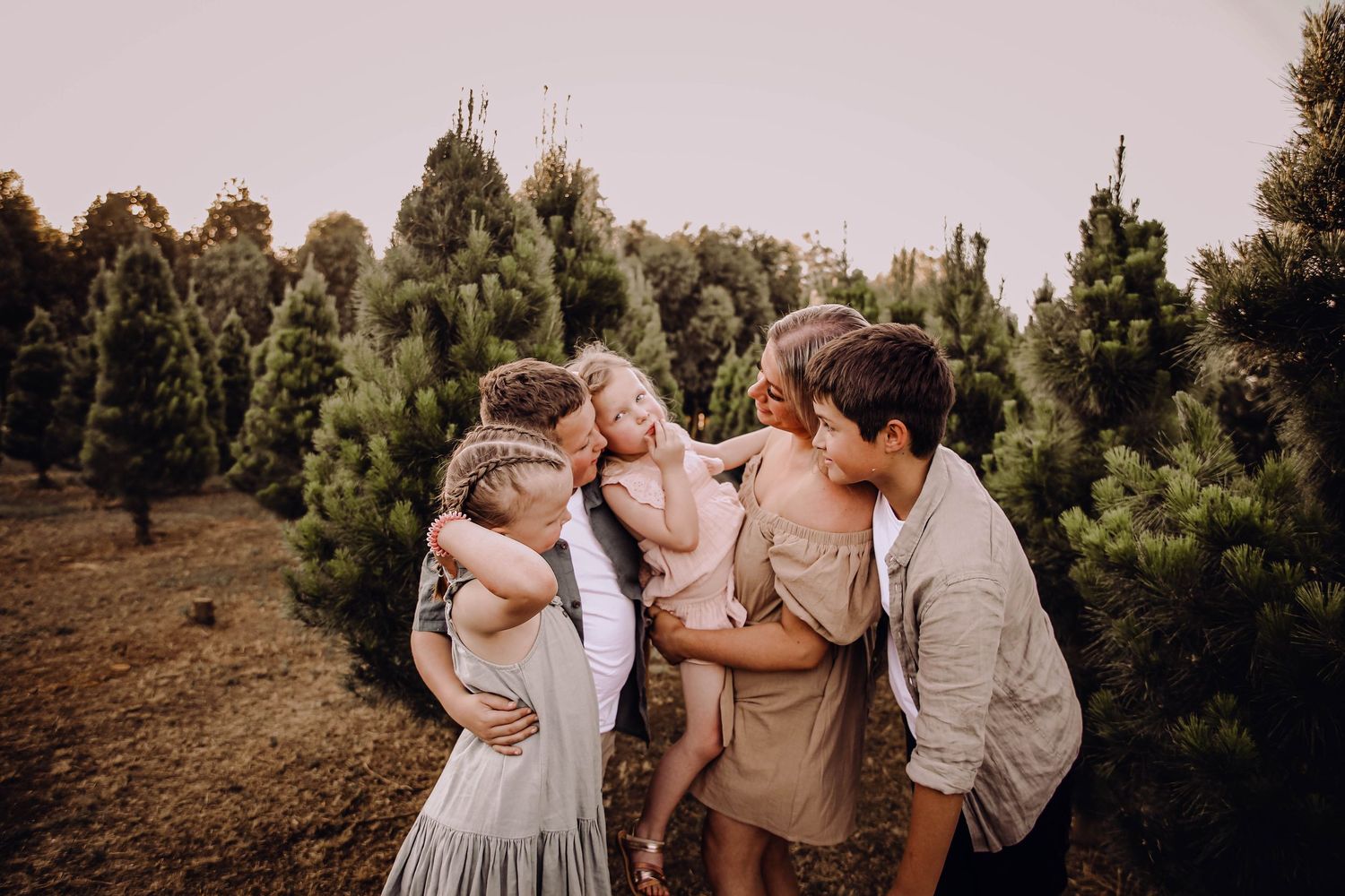 Family sharing an intimate moment together outdoors among pine trees at sunset. Family Photography