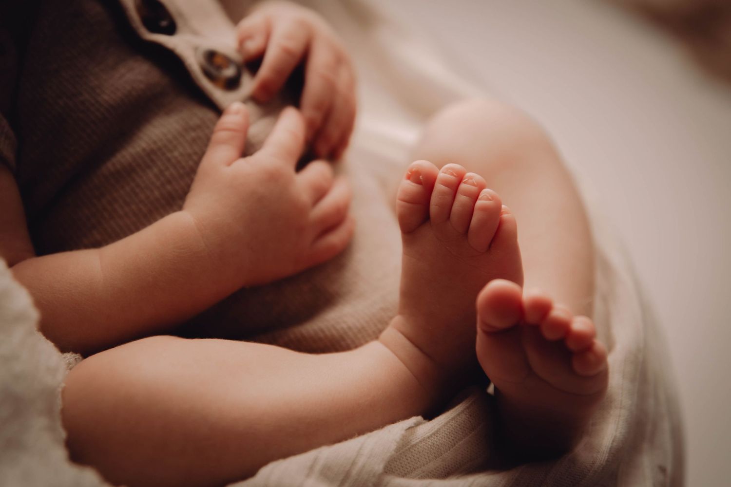 Close-up of tiny baby feet and hands on soft fabric. Newborn Photography