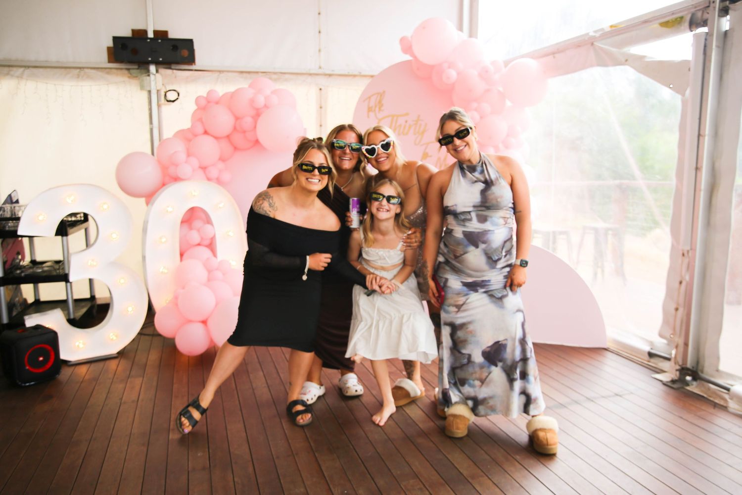 Group photo session with pink balloon decorations and wooden flooring.
