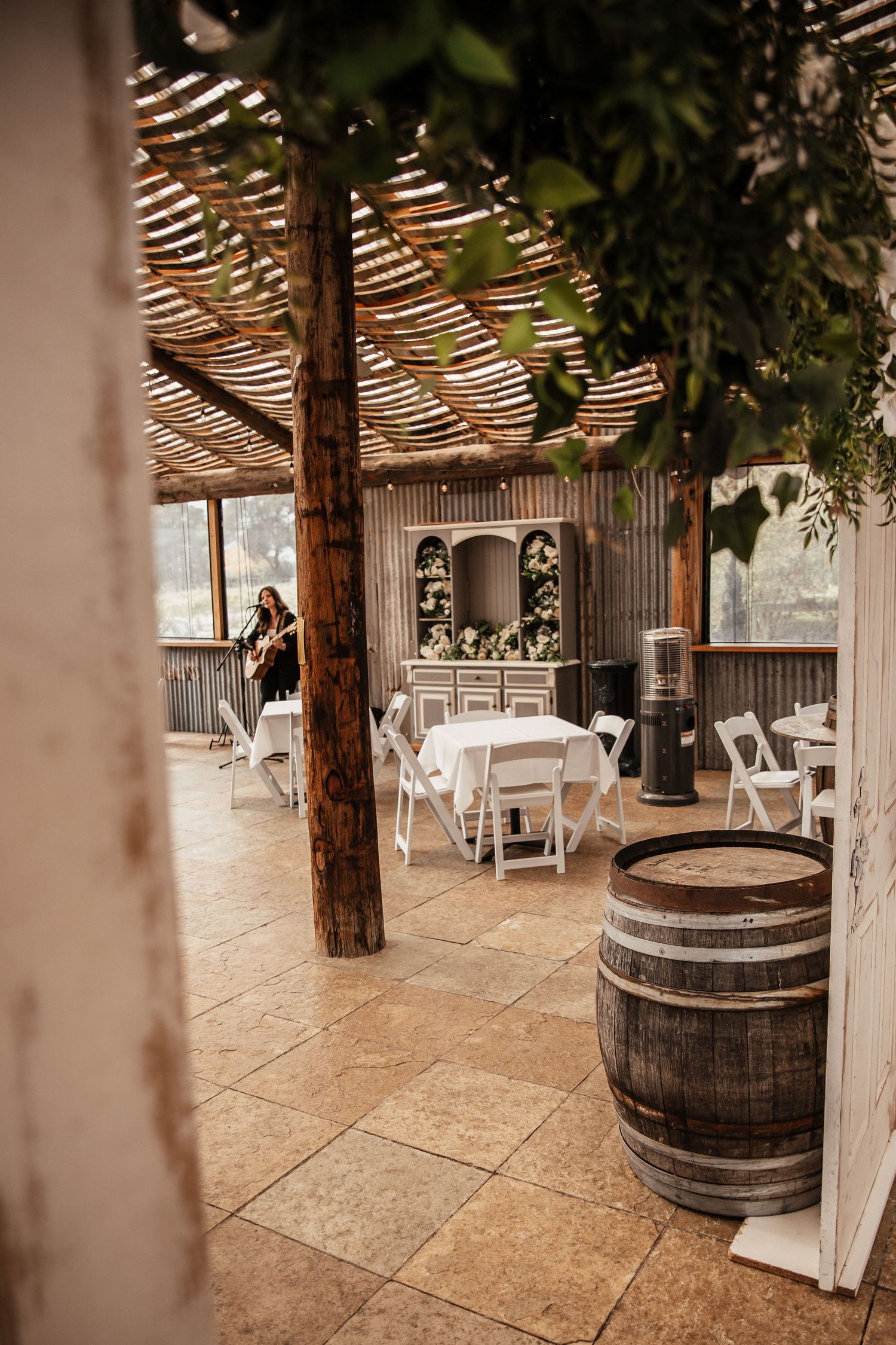 Rustic wedding venue with wooden beams, barrels and hanging greenery. Wedding photography