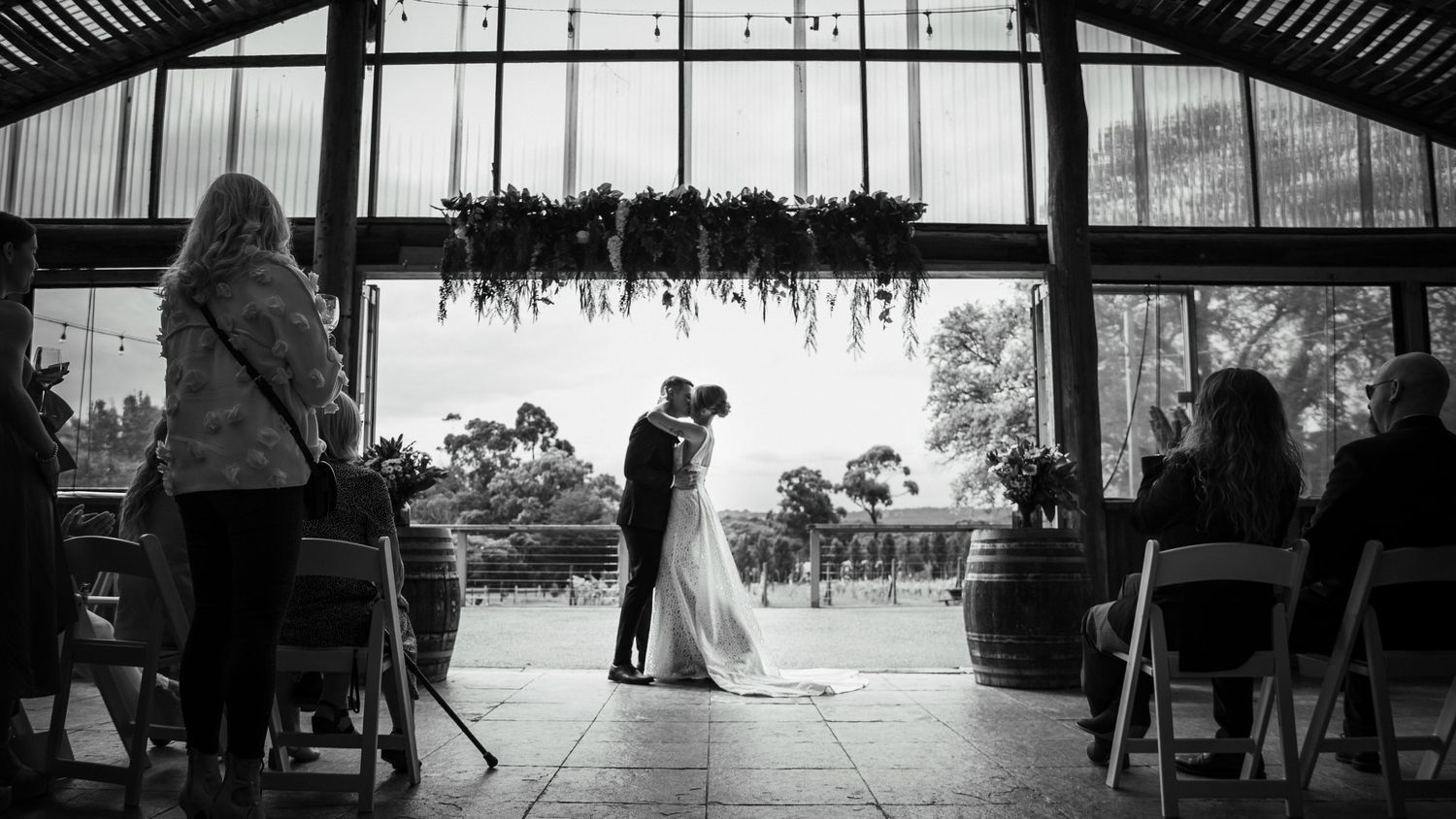 A wide-angle silhouette view of a barn wedding reception space with dramatic lighting. Wedding photography