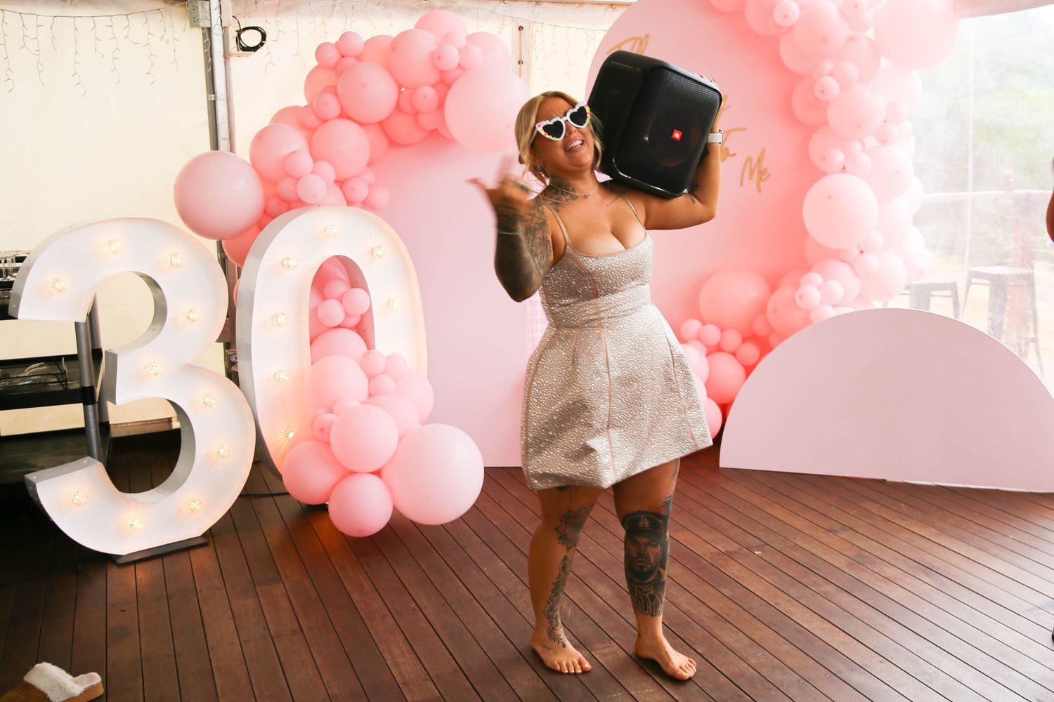 A series of fun dance poses on a wooden deck with pink balloon decorations in the background.