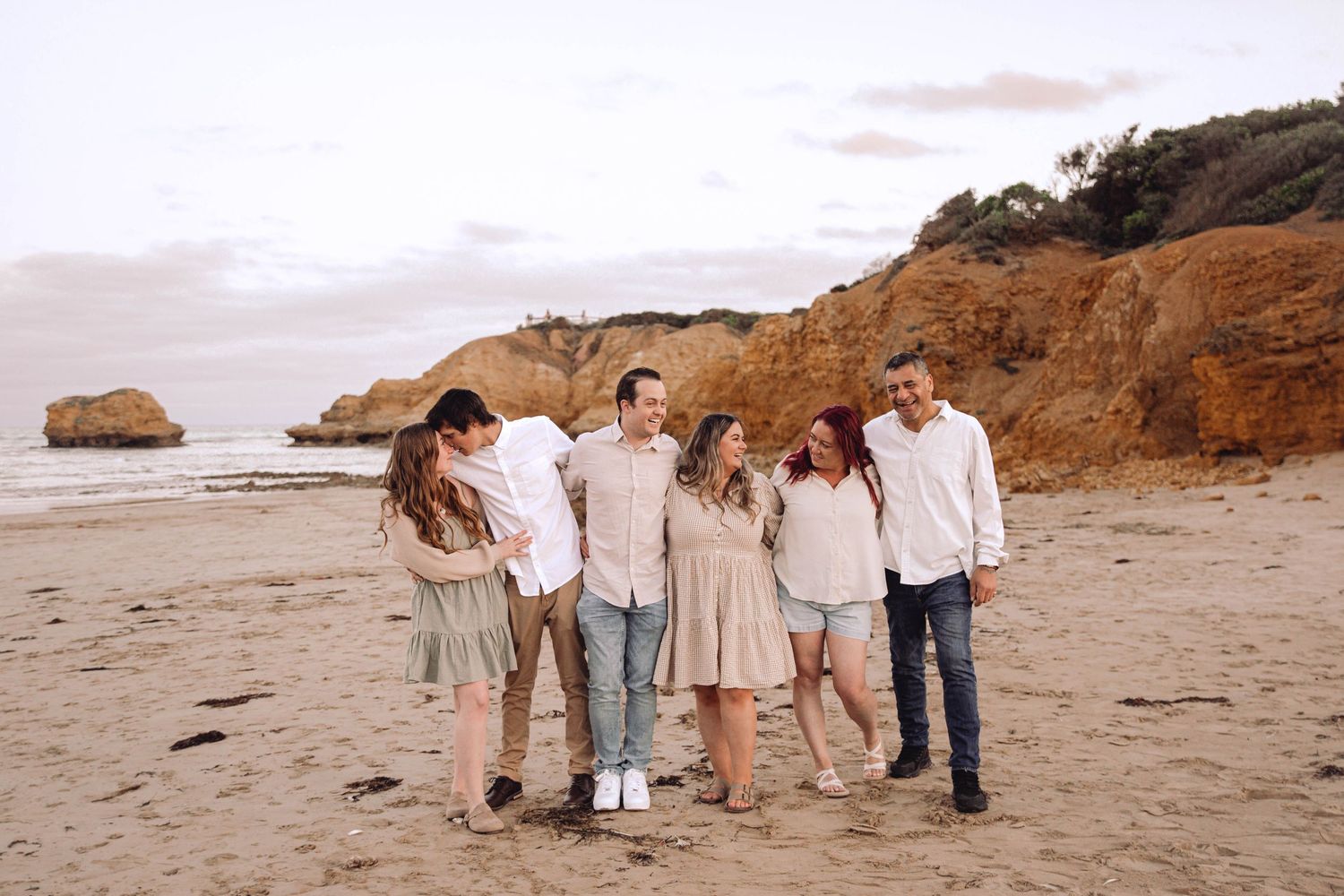 Extended family walking together on beach during golden hour photography session.