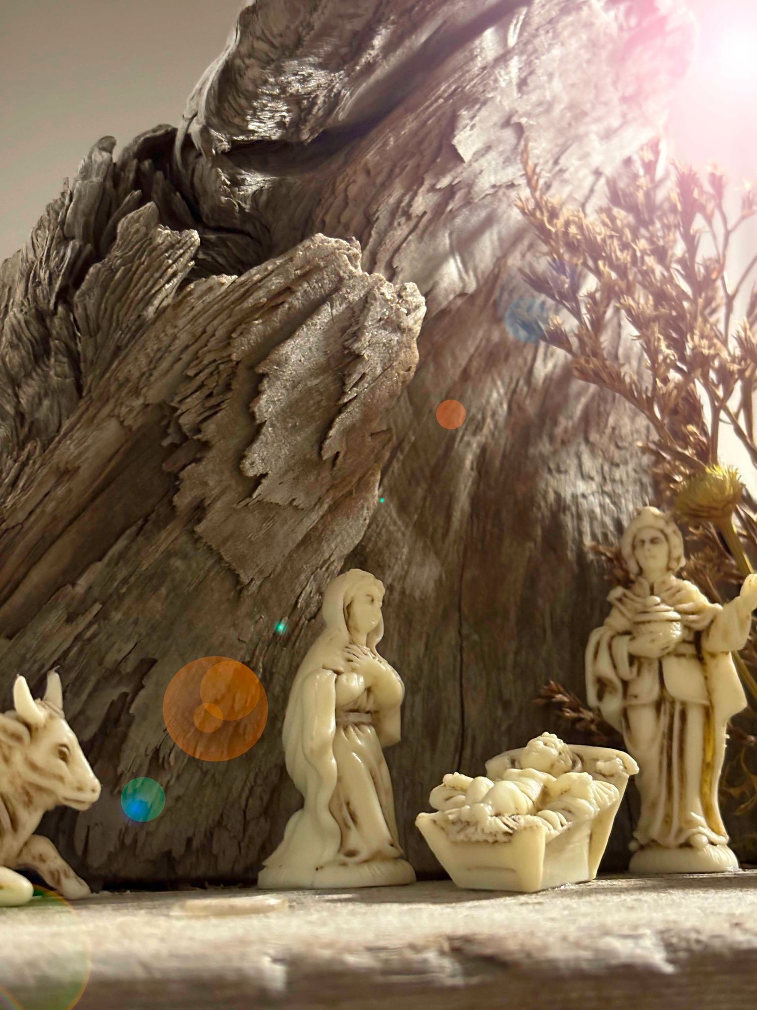 Clay sculptures of religious figures arranged in a nativity scene display against a rocky backdrop with dramatic lighting.