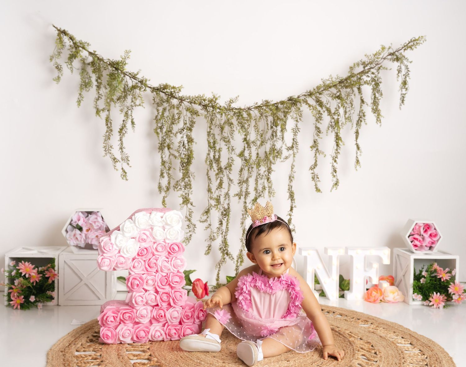 Floral themed birthday setup with hanging greenery and pink rose decorations.