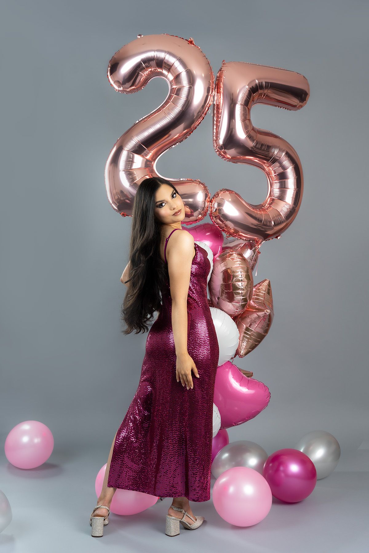 Festive pose with rose gold '25' balloons and magenta sequin dress.