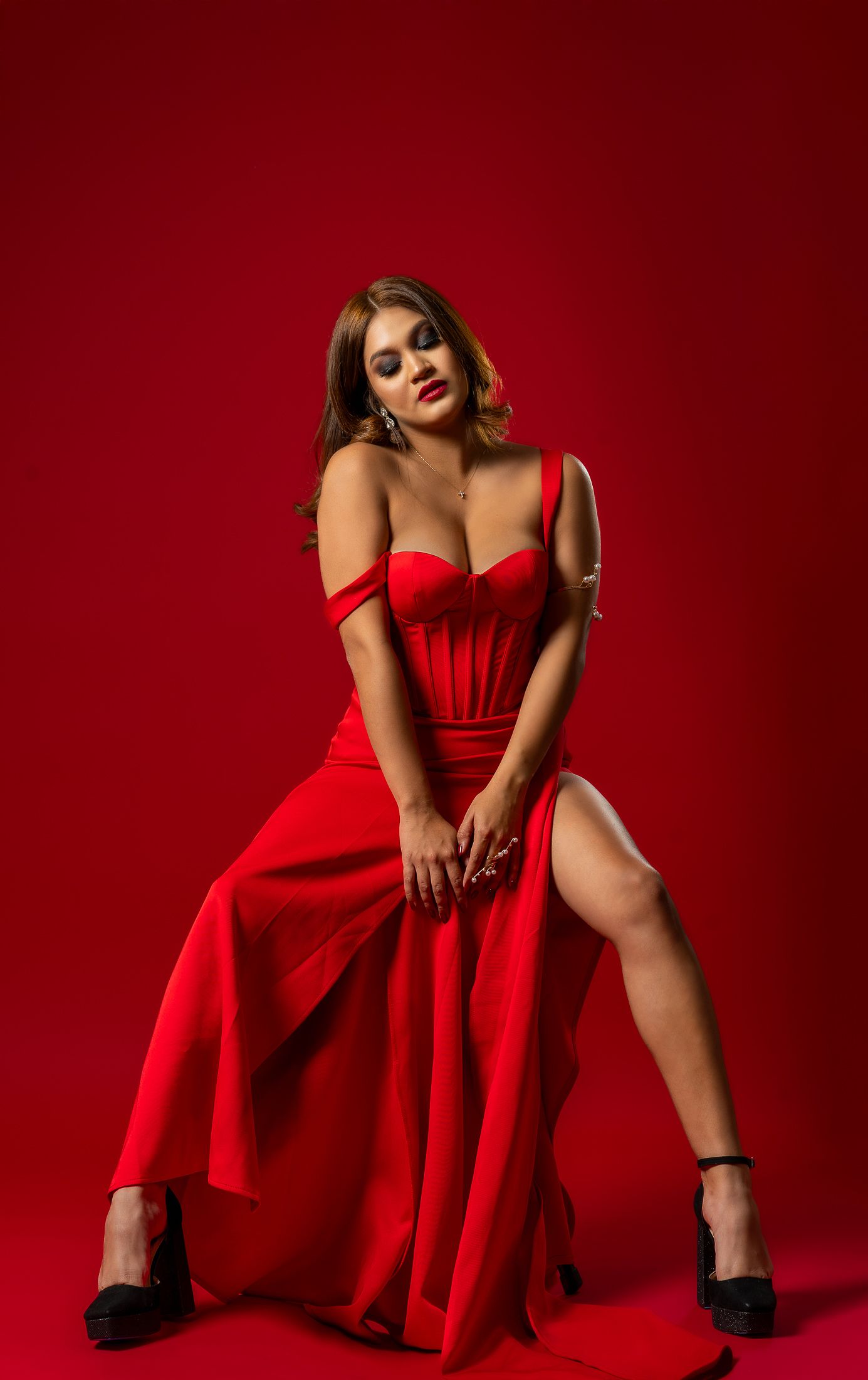 Fashion photography with model in striking red gown against matching backdrop.