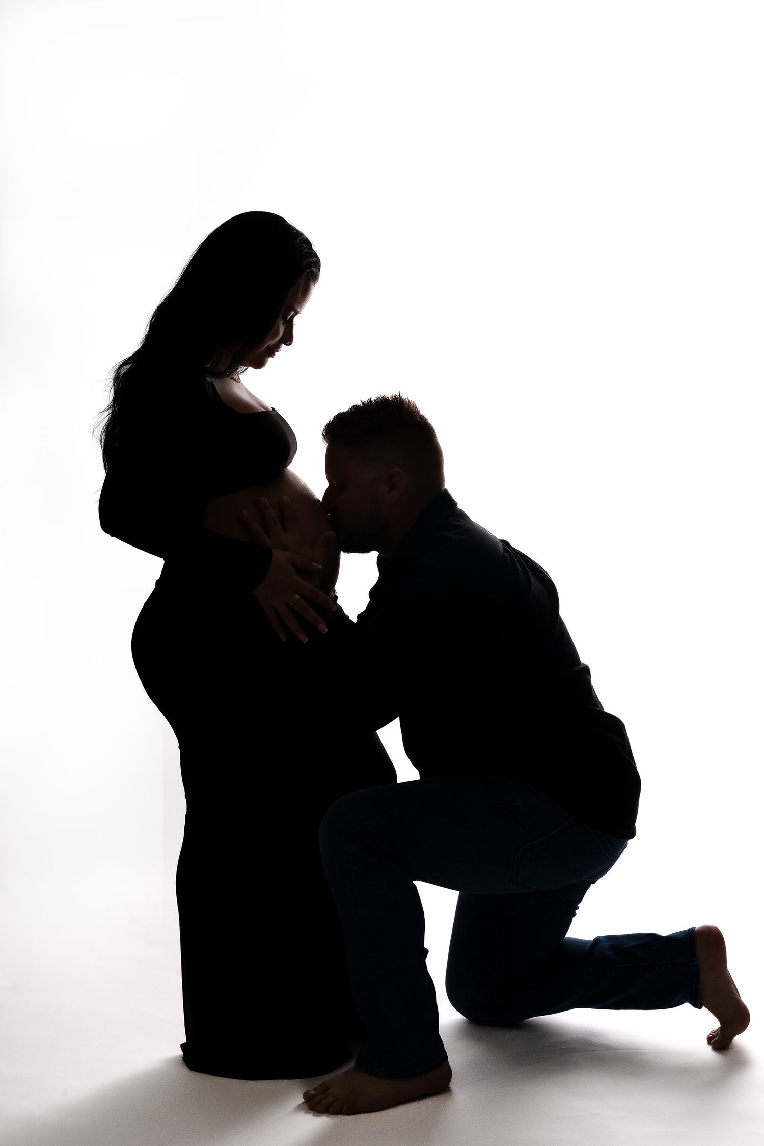 Artistic silhouette series of an expectant couple creating dramatic shadows on white background.