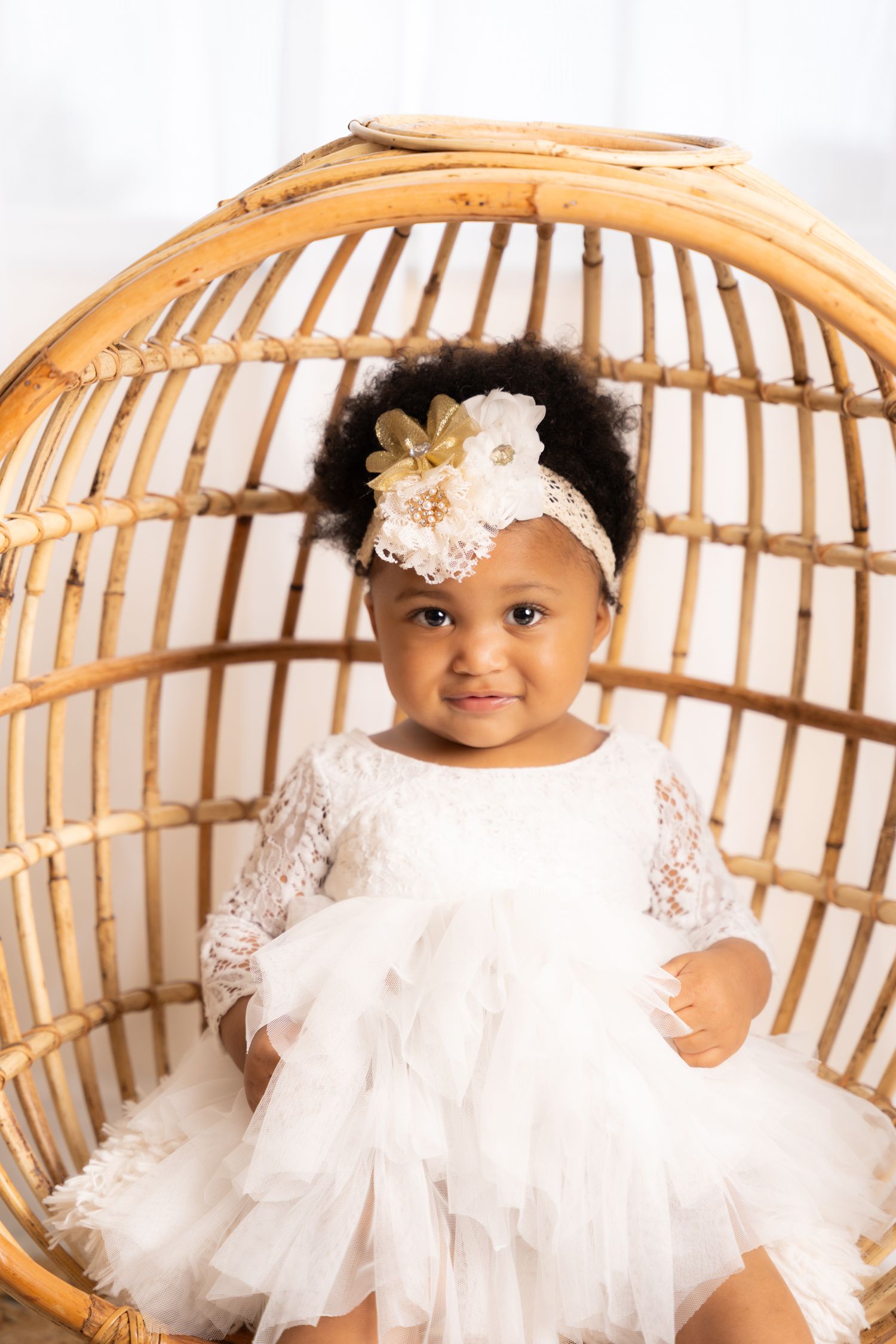 White lace dress celebration photoshoot with rattan chair and soft lighting.