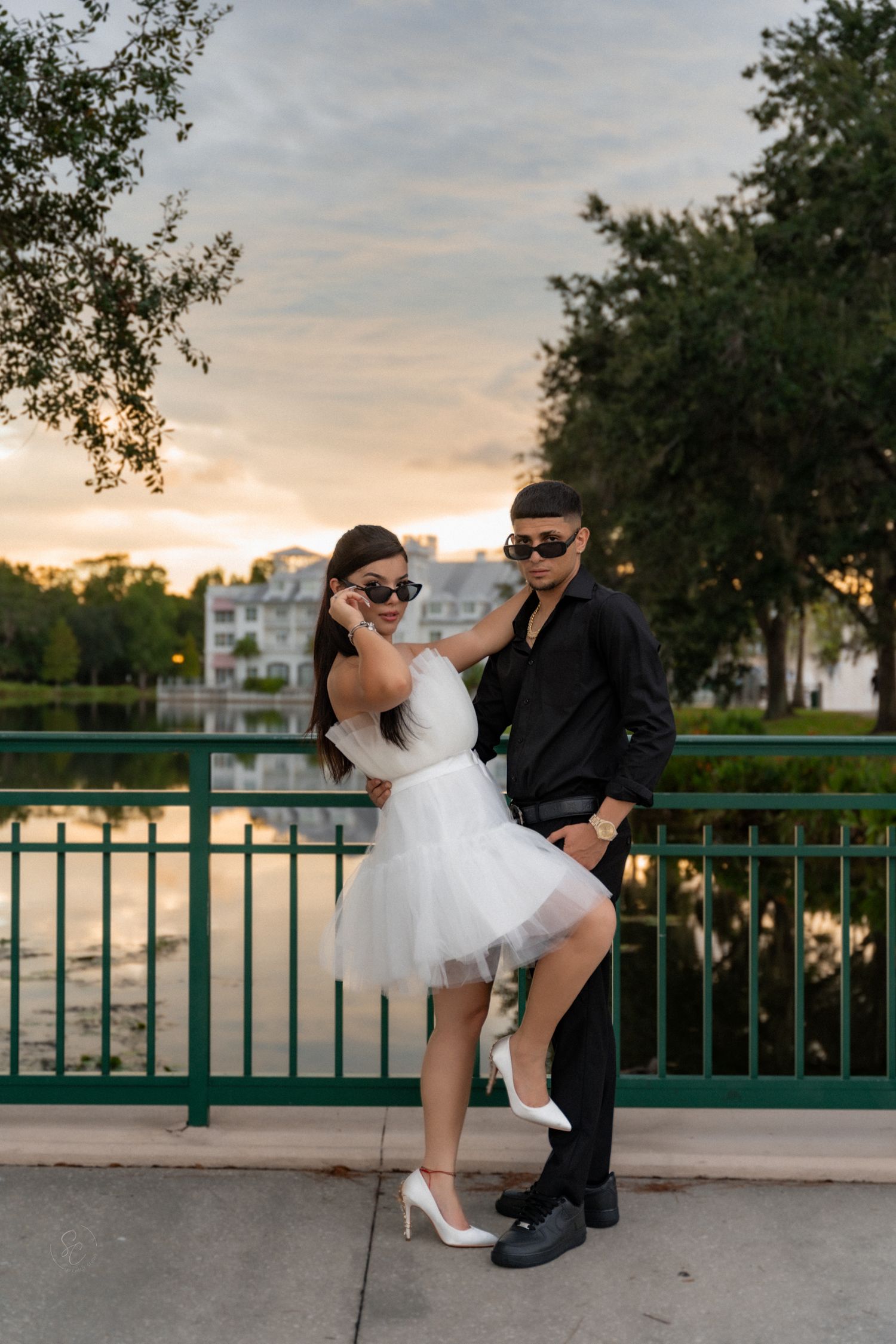 Sunset photoshoot on a green railing bridge with couple in formal wear.