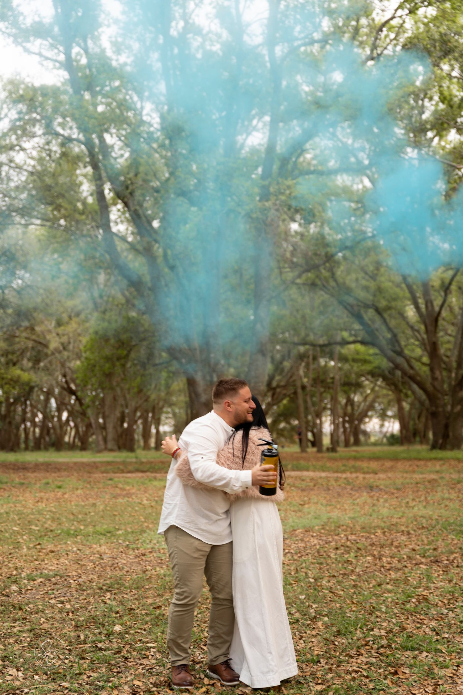 Romantic outdoor couple photography session with smoke bombs creating dreamy teal atmosphere.