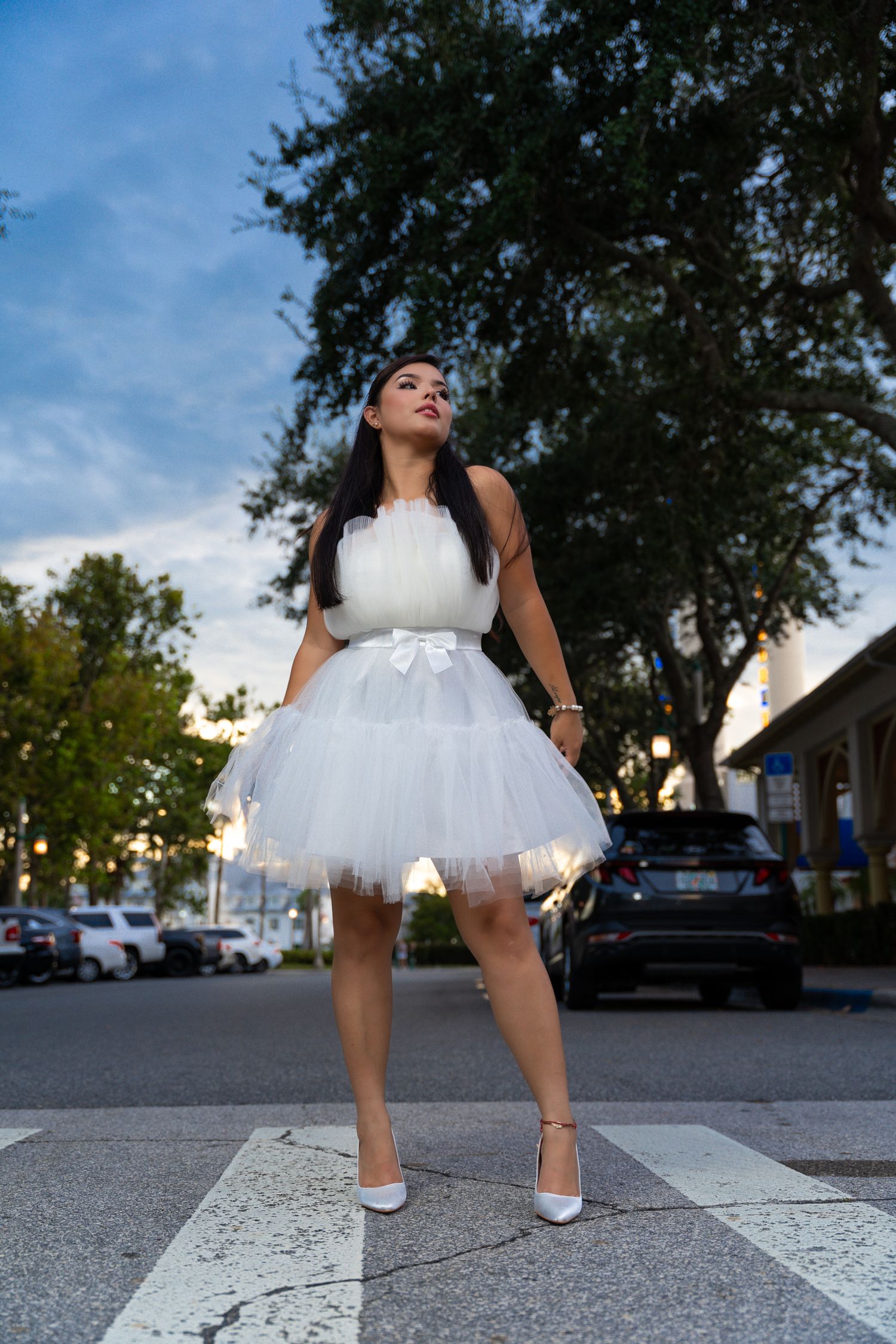 White tulle dress and heels photographed from ground level in urban setting.
