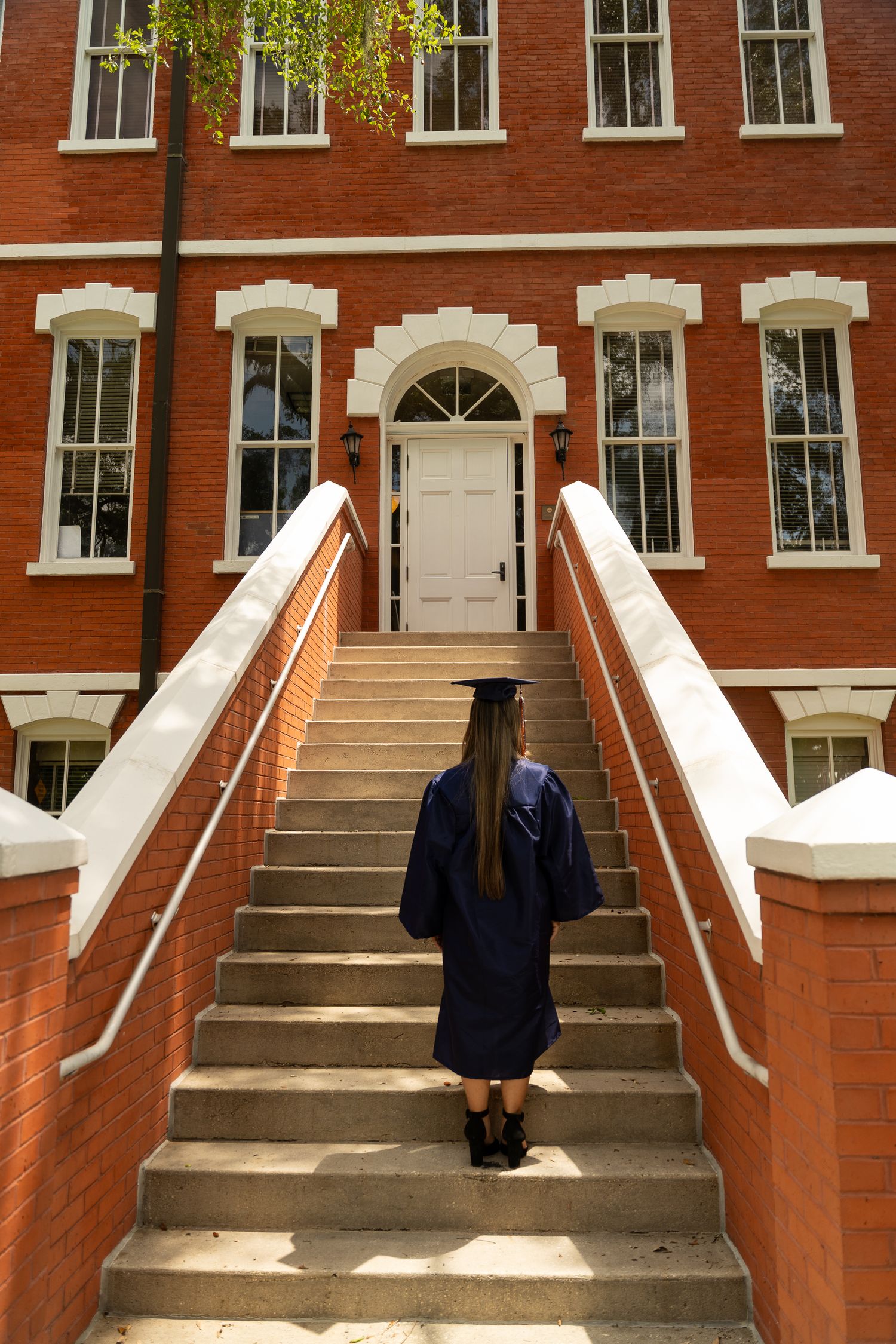 Symmetrical red brick building entrance with multiple white-trimmed doorways and steps leading to separate entrances.