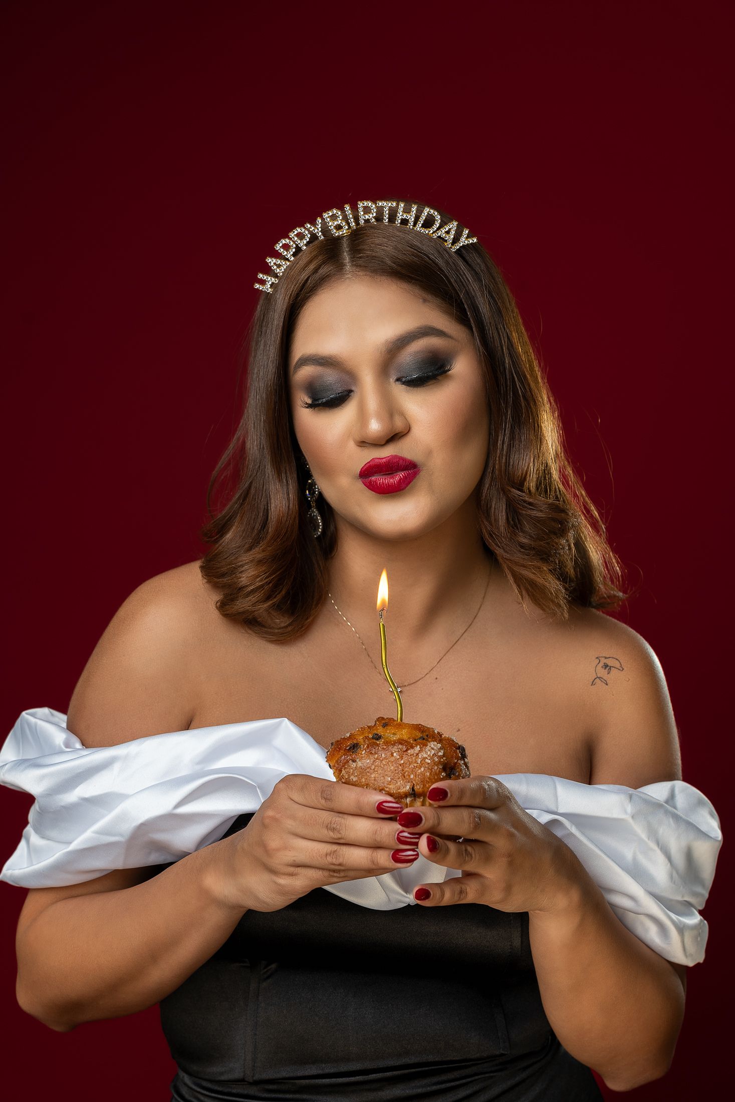 Birthday celebration photo with cupcake and candle against red background.