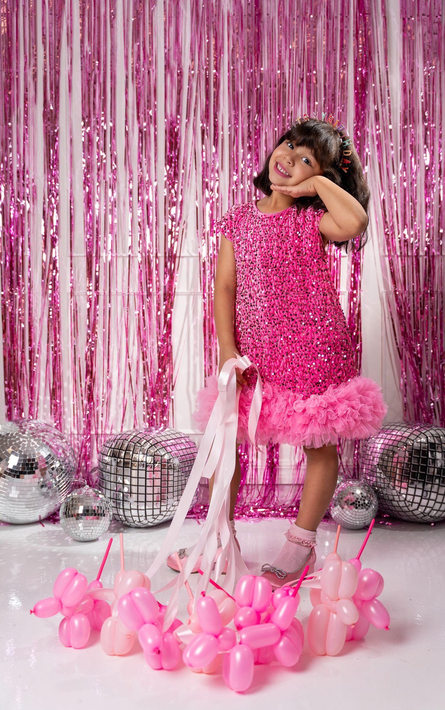Pink party setup with silver disco balls and balloon decorations against shimmering backdrop.