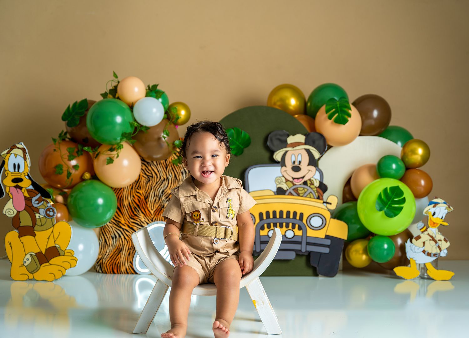 Safari themed birthday setup with green and gold balloons and cartoon character decorations.