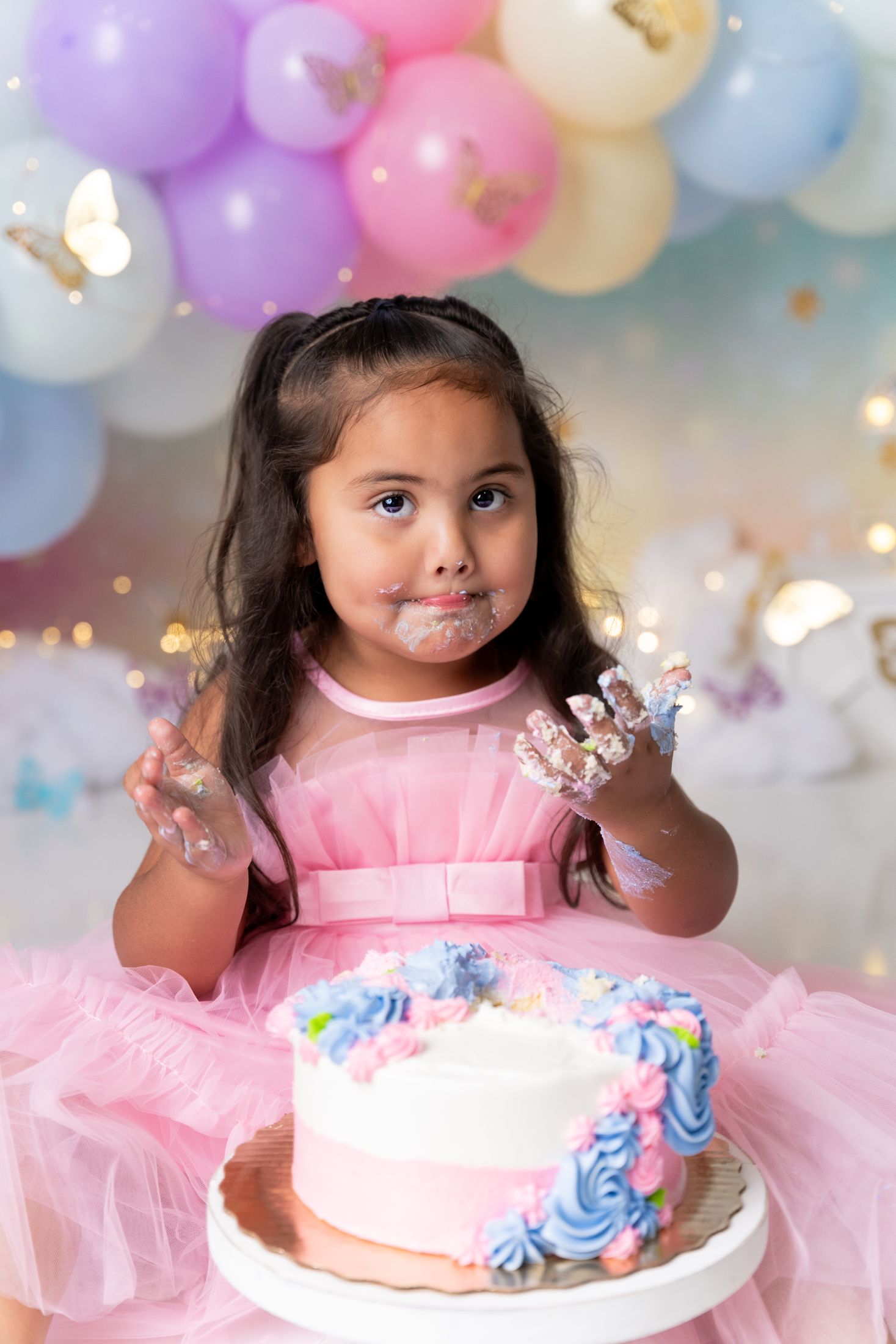 Cake smash photo session with pink tulle dress and decorated birthday cake.