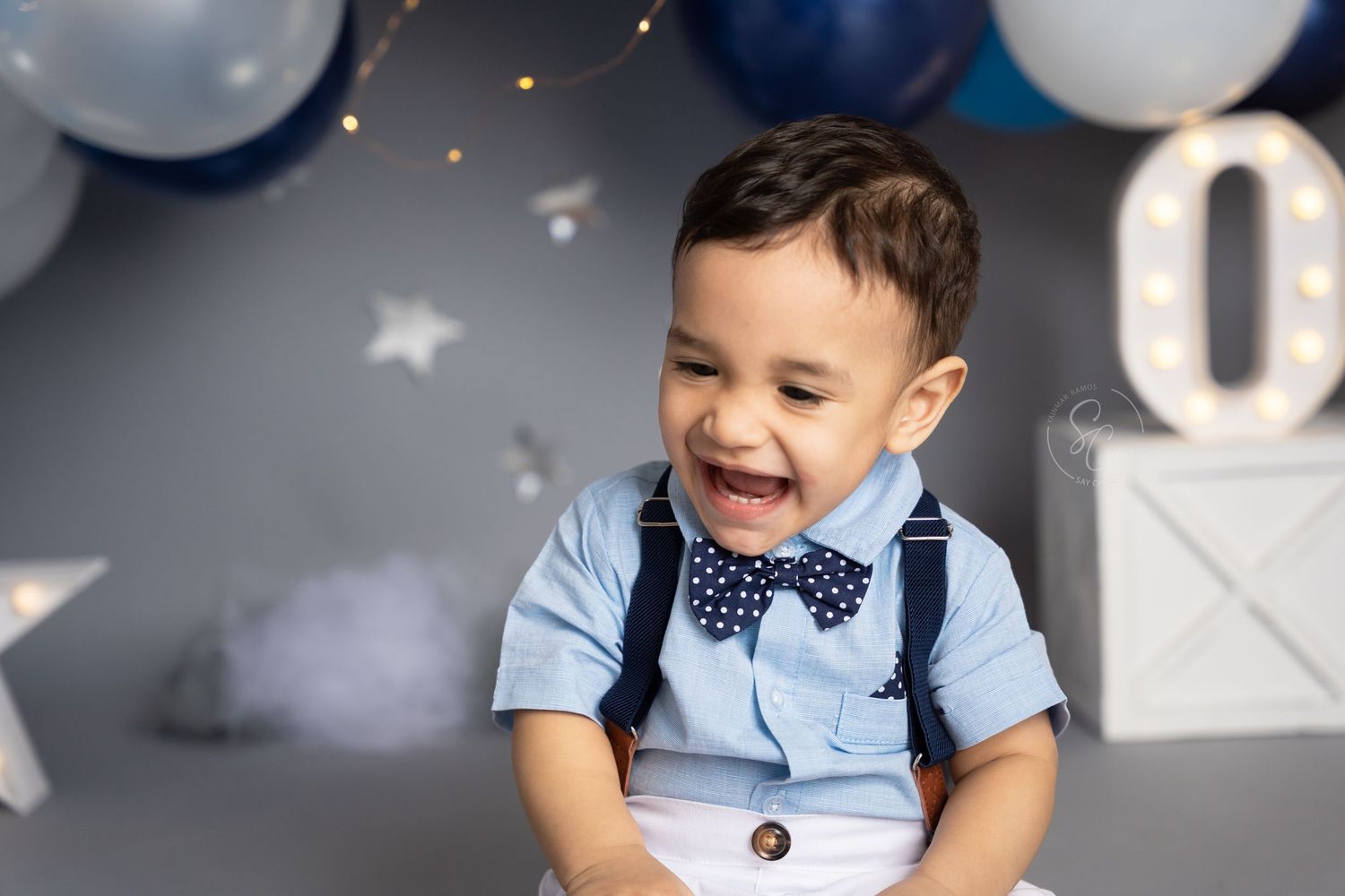 First birthday photoshoot featuring elegant balloon arch and twinkling fairy lights.