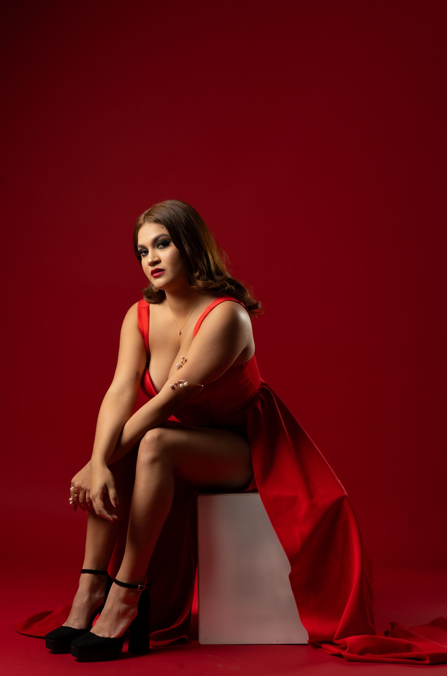 Artistic portrait series with figure in red fabric against deep burgundy background.