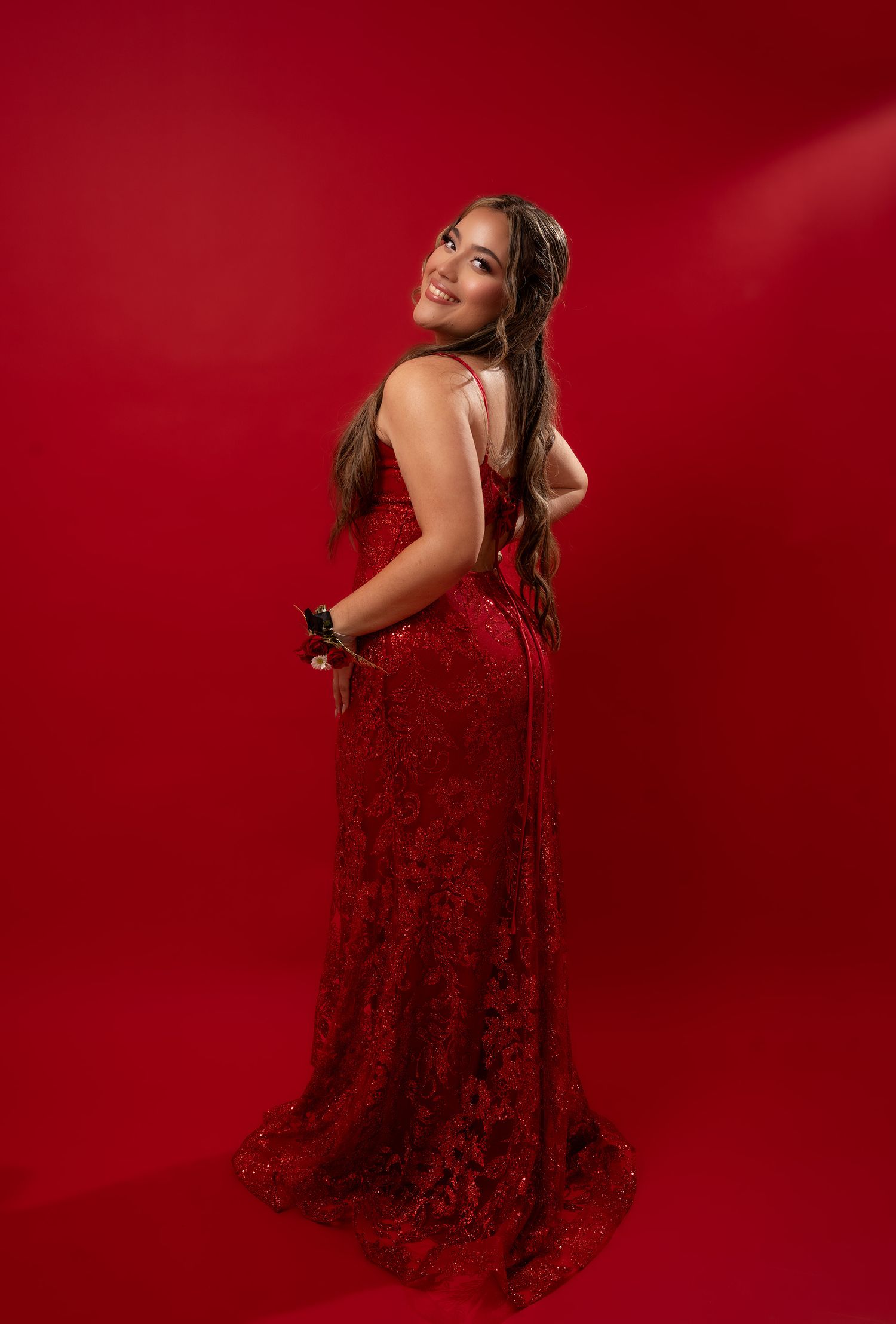 Elegant poses in a sequined red dress against deep crimson backdrop.