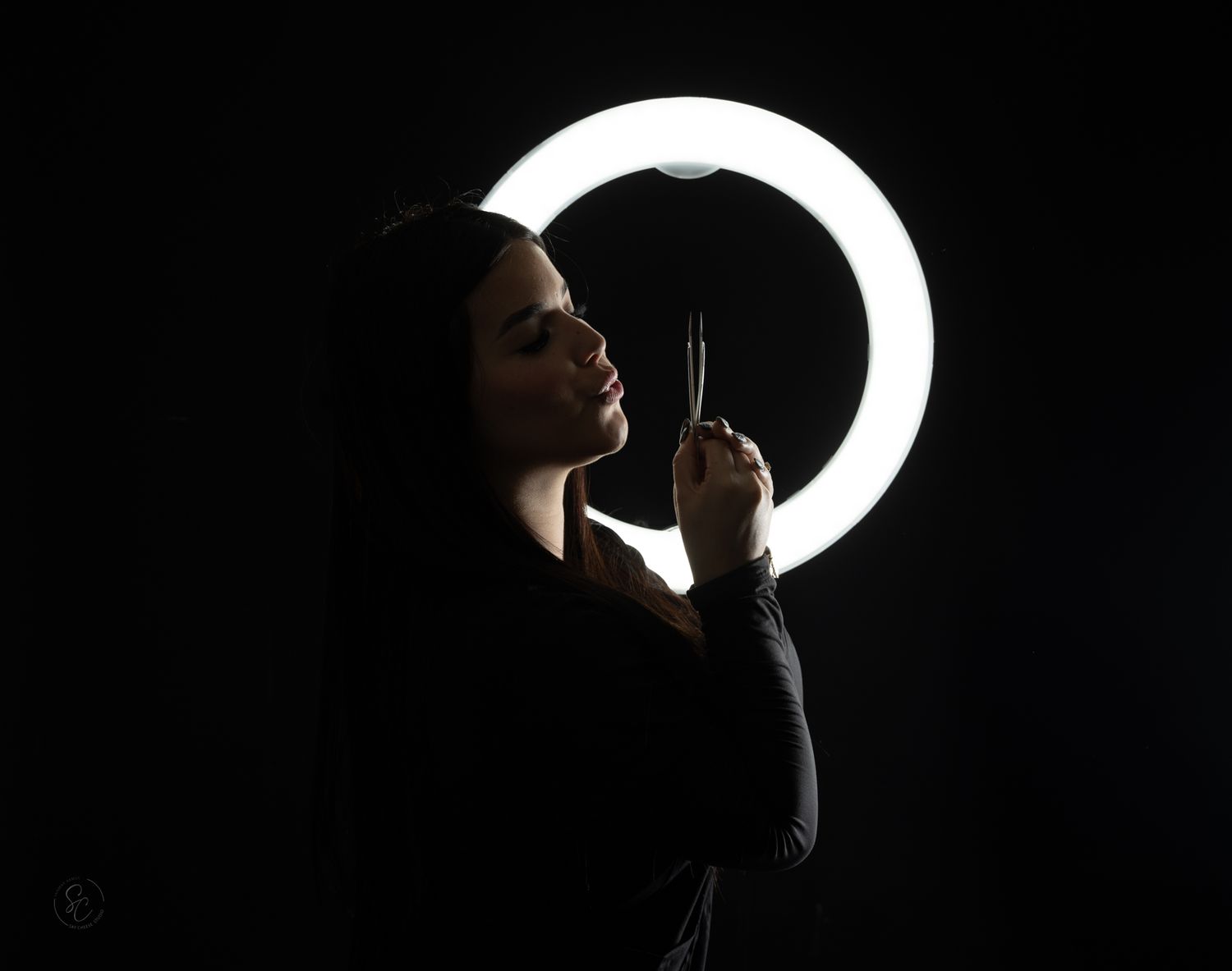 Silhouetted profile portrait with dramatic ring light creating a halo effect.