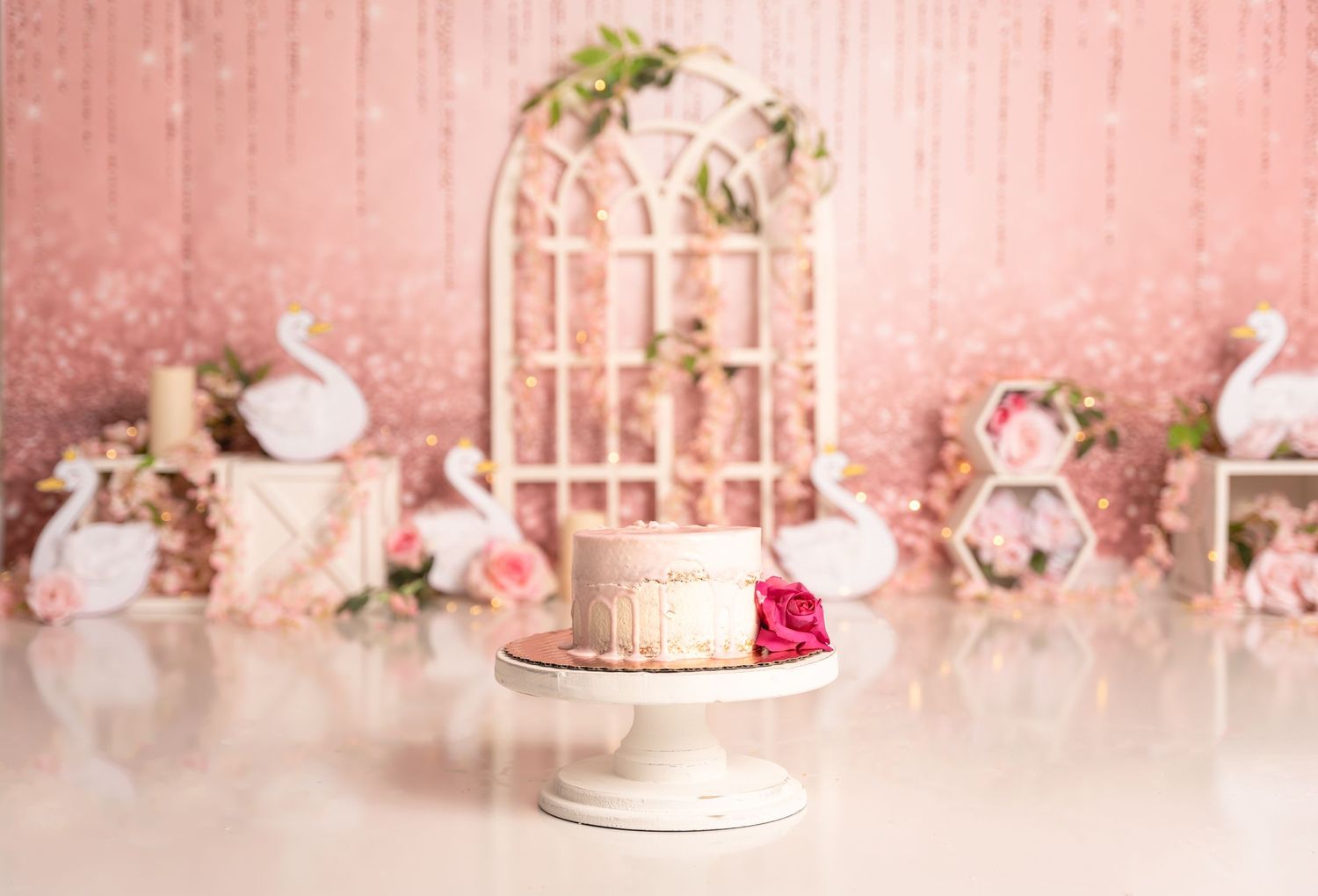 Pink backdrop with delicate floral decorations and party setup.