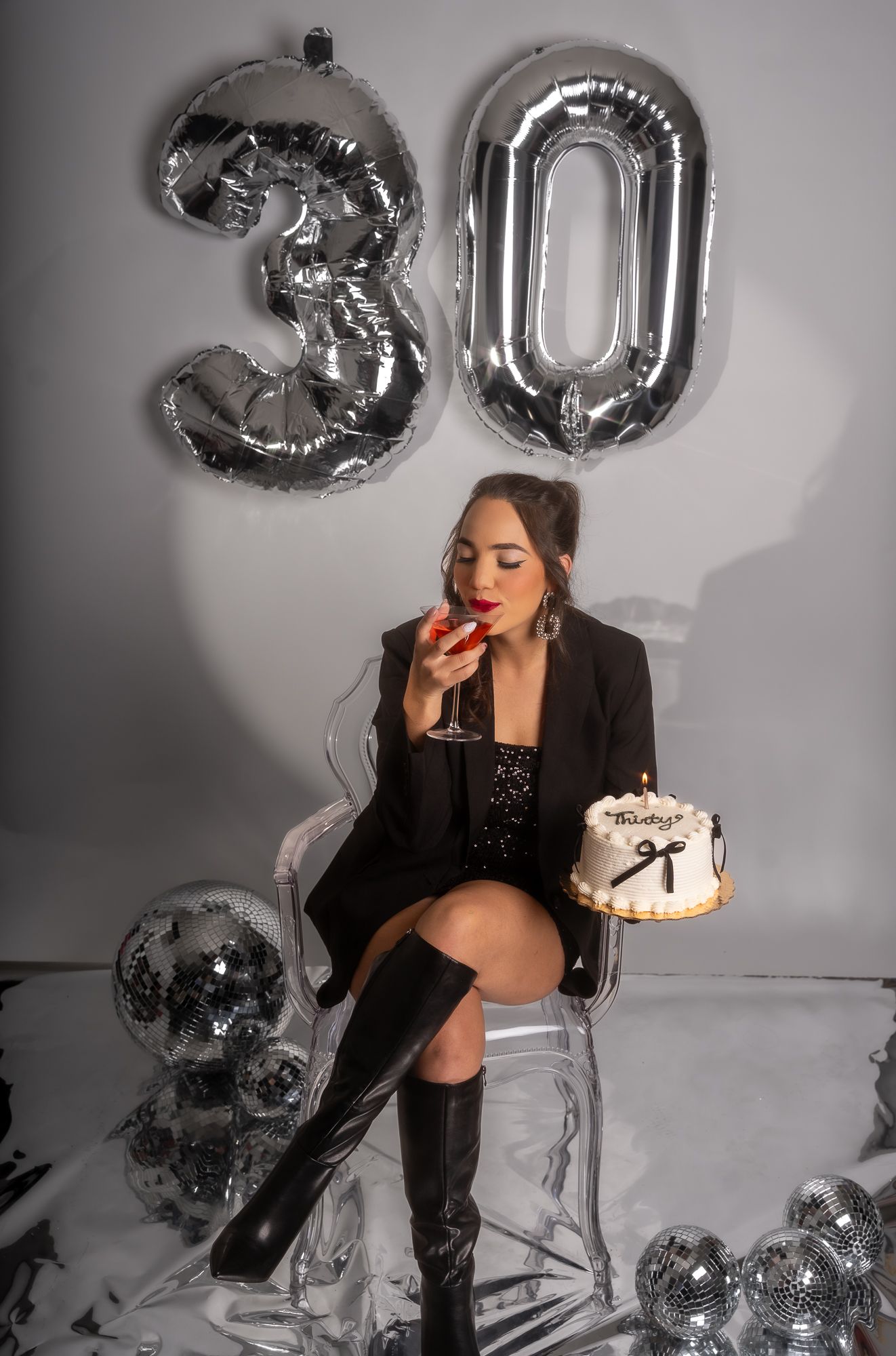 Elegant birthday setup with metallic balloons, cake, and black formal attire.