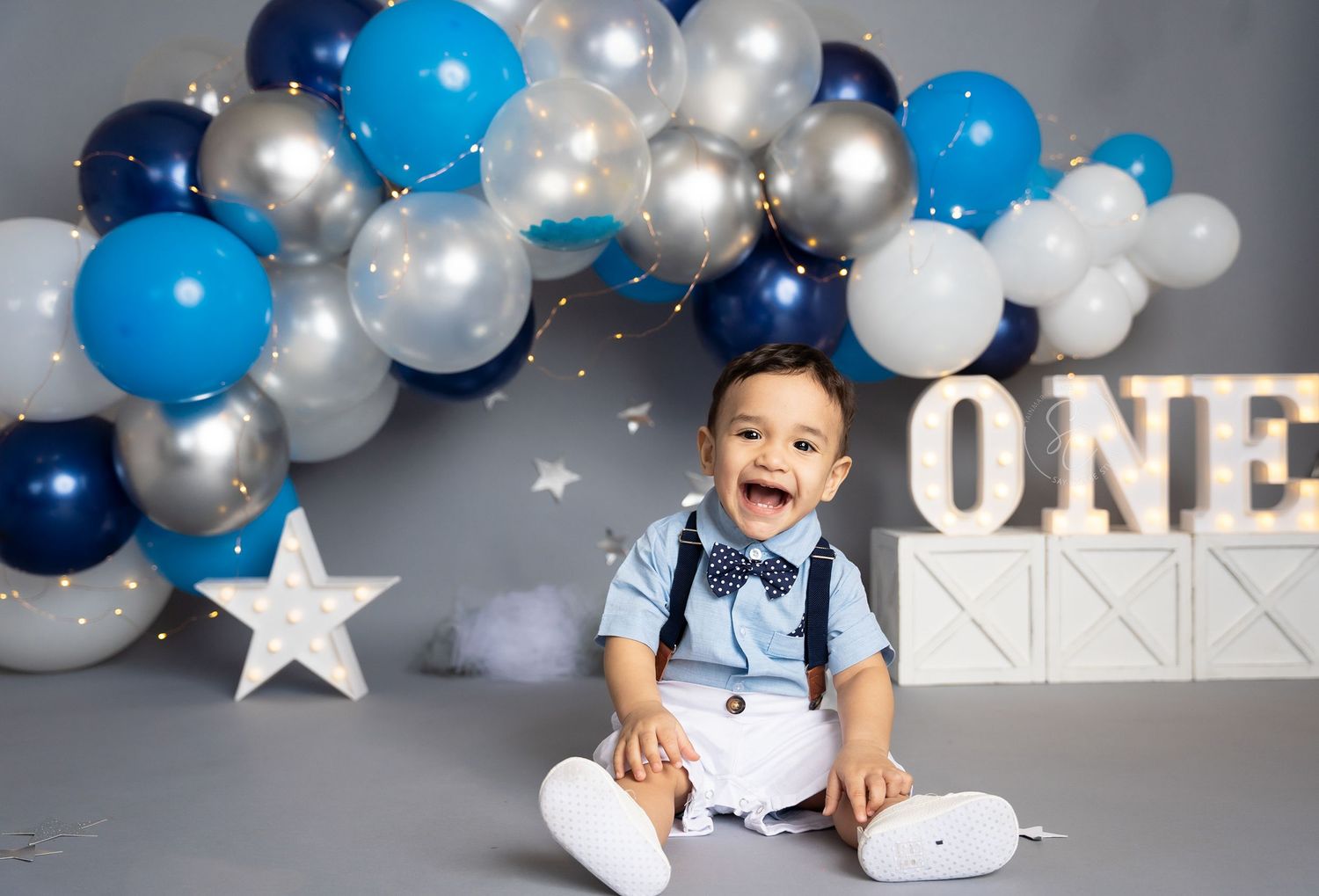 Birthday setup with 'ONE' lettering and star decorations against balloon backdrop.